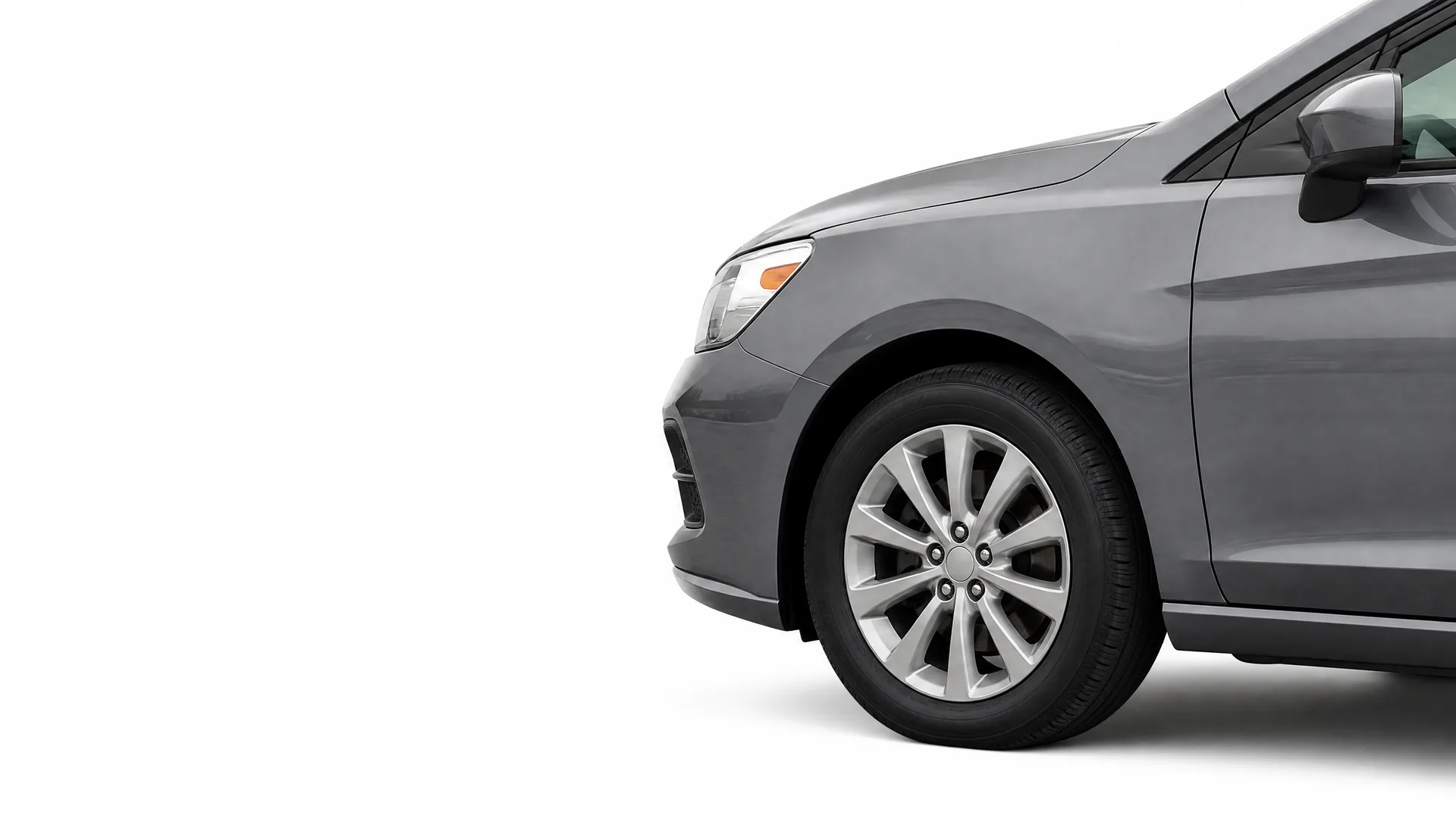 Front left portion of a gray sedan, showing the headlight, front wheel with alloy rim, door and side mirror, against a plain white background.