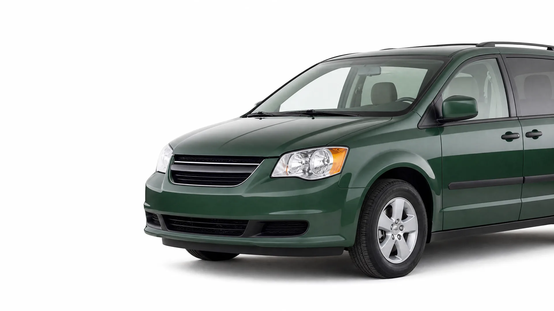 A dark green minivan photographed from the front left against a plain white background, with the rear of the vehicle cropped out of frame.