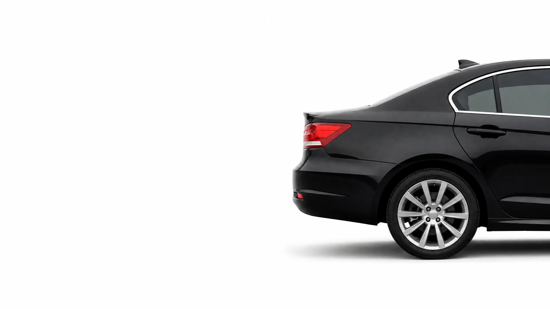Rear three-quarter view of a black four-door sedan with alloy wheels, shown against a plain white background with a soft shadow beneath it.
