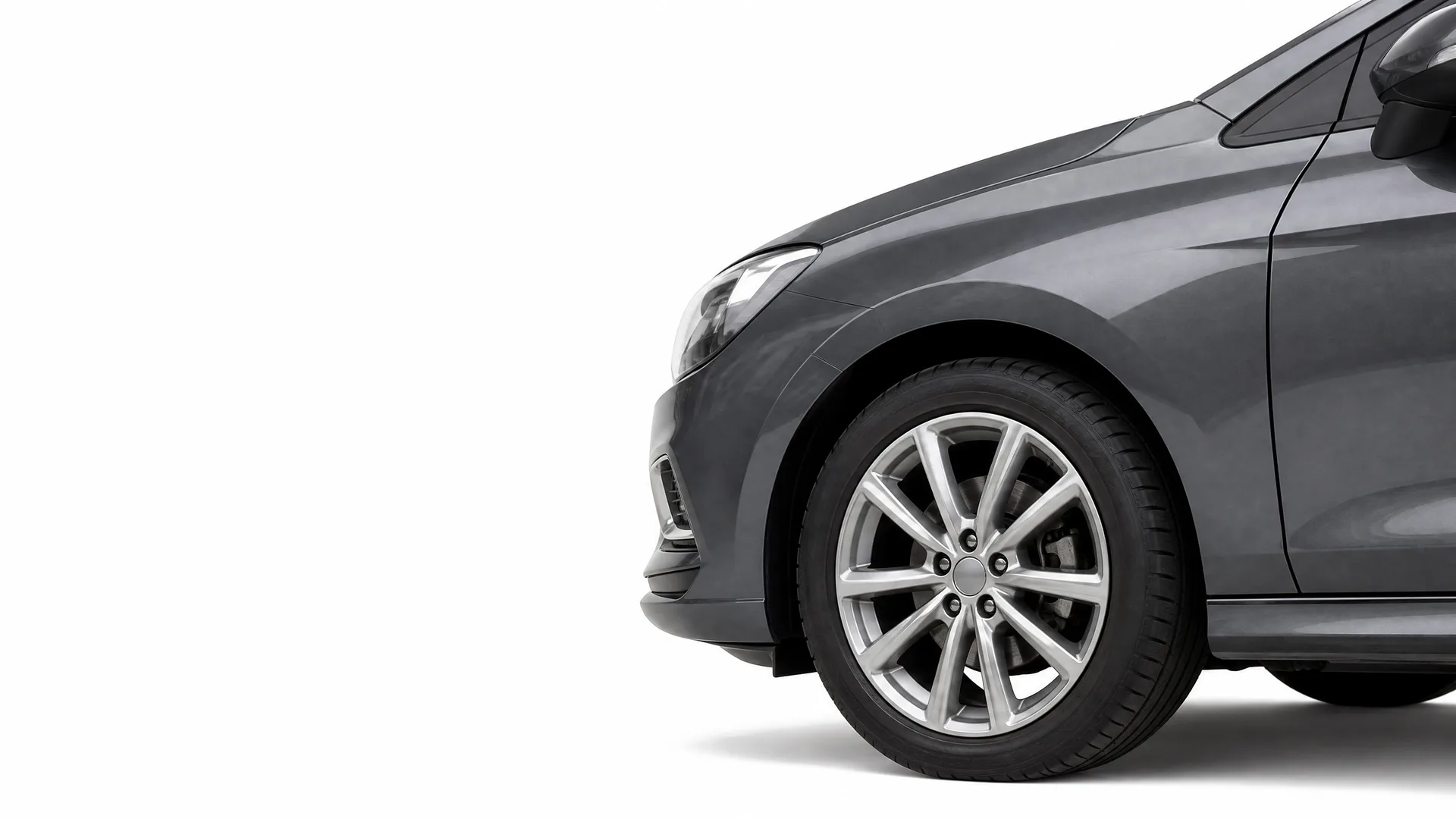 Front portion of a dark grey car, showing the front wheel with a multi-spoke alloy rim, headlight and front door, isolated on a white background.
