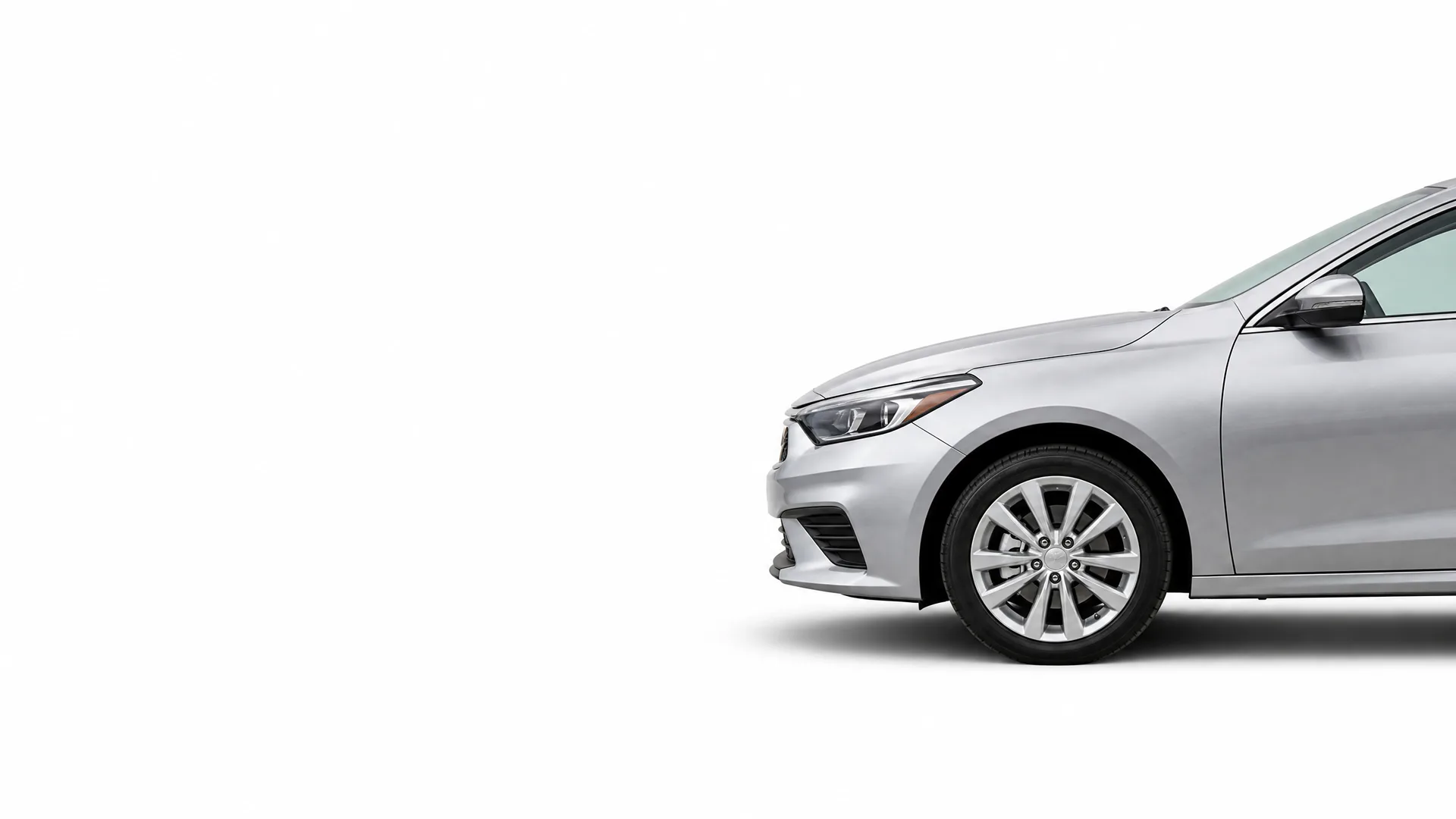 Front half of a silver four-door sedan, shown in profile against a plain white background with a soft shadow beneath the wheel.