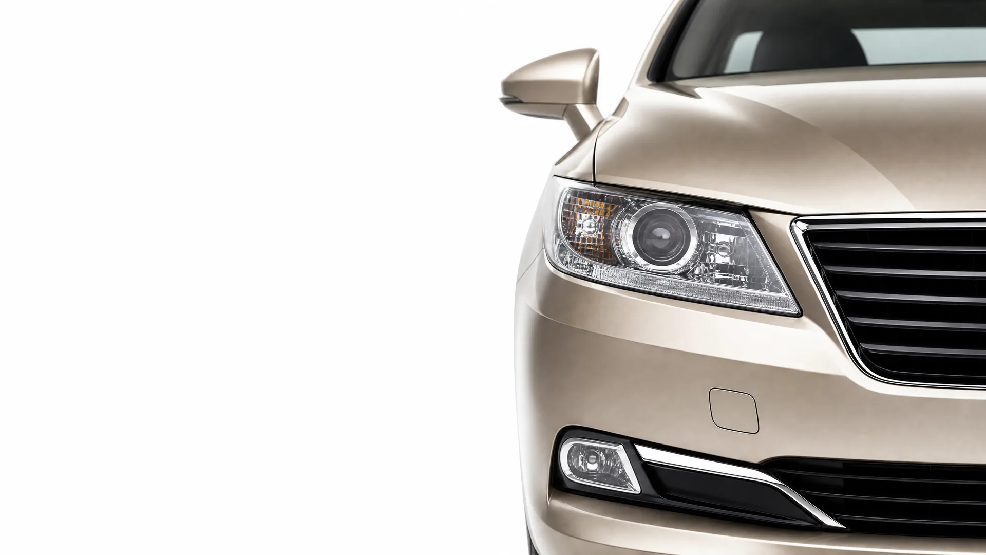 Front right portion of a beige sedan, showing the headlight, grille, fog light, and side mirror, against a plain white background.
