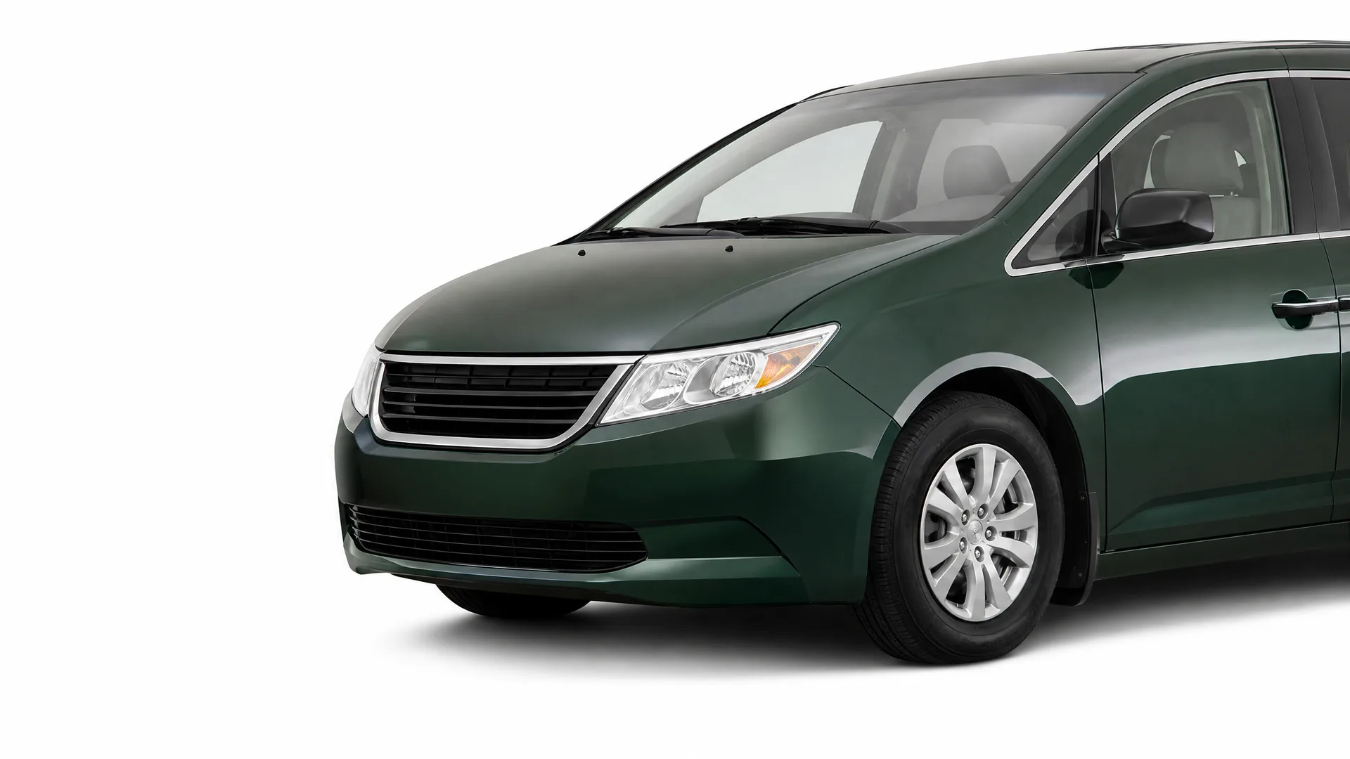 Front three-quarter view of a dark green minivan, partially cropped, on a plain white background.