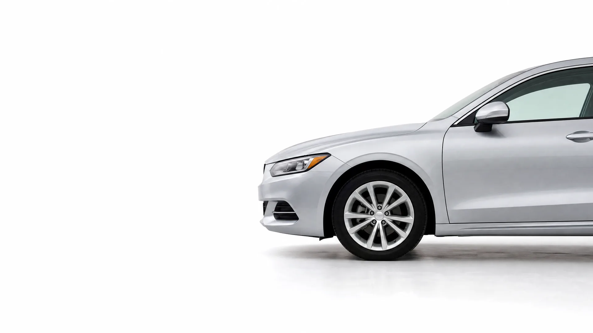 Front half of a silver four-door sedan photographed in profile against a plain white studio background, with the rear of the car cropped off at the right edge.