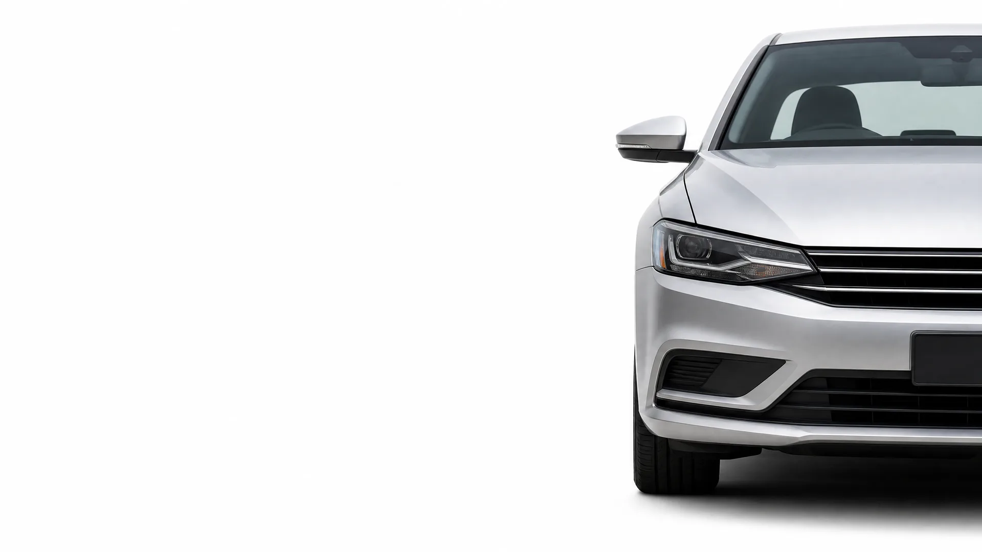 Front left portion of a silver sedan, including headlight, grille, bumper and side mirror, shown against a plain white background.