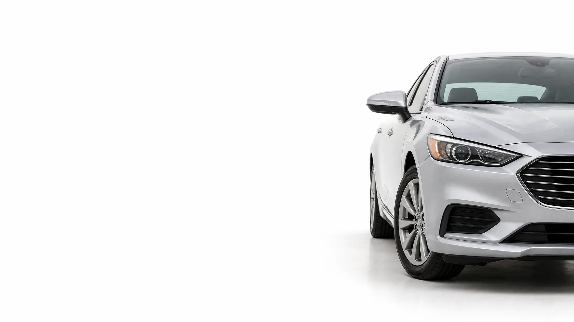Front right portion of a silver four-door sedan photographed against a plain white studio background, with the rest of the frame empty.