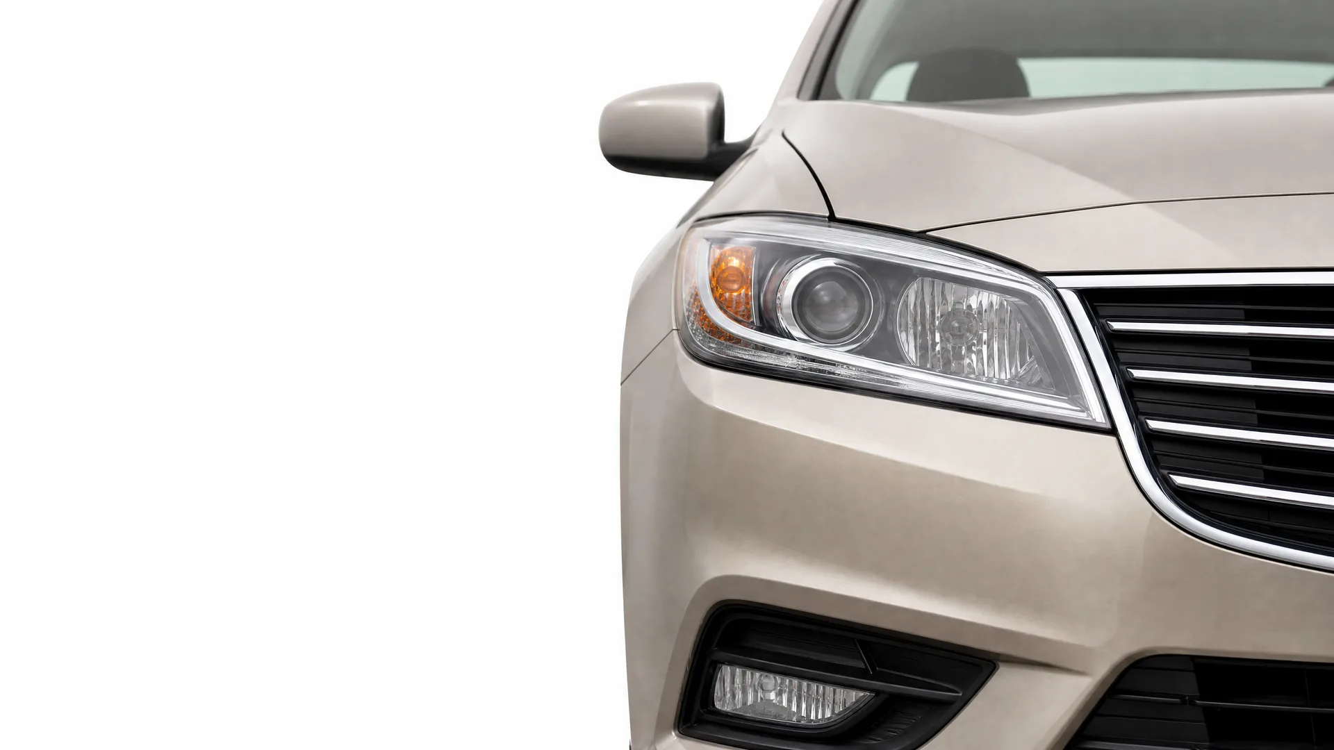 Close-up of the front right corner of a beige sedan, showing the headlight, grille, fog light and side mirror, isolated on a white background.