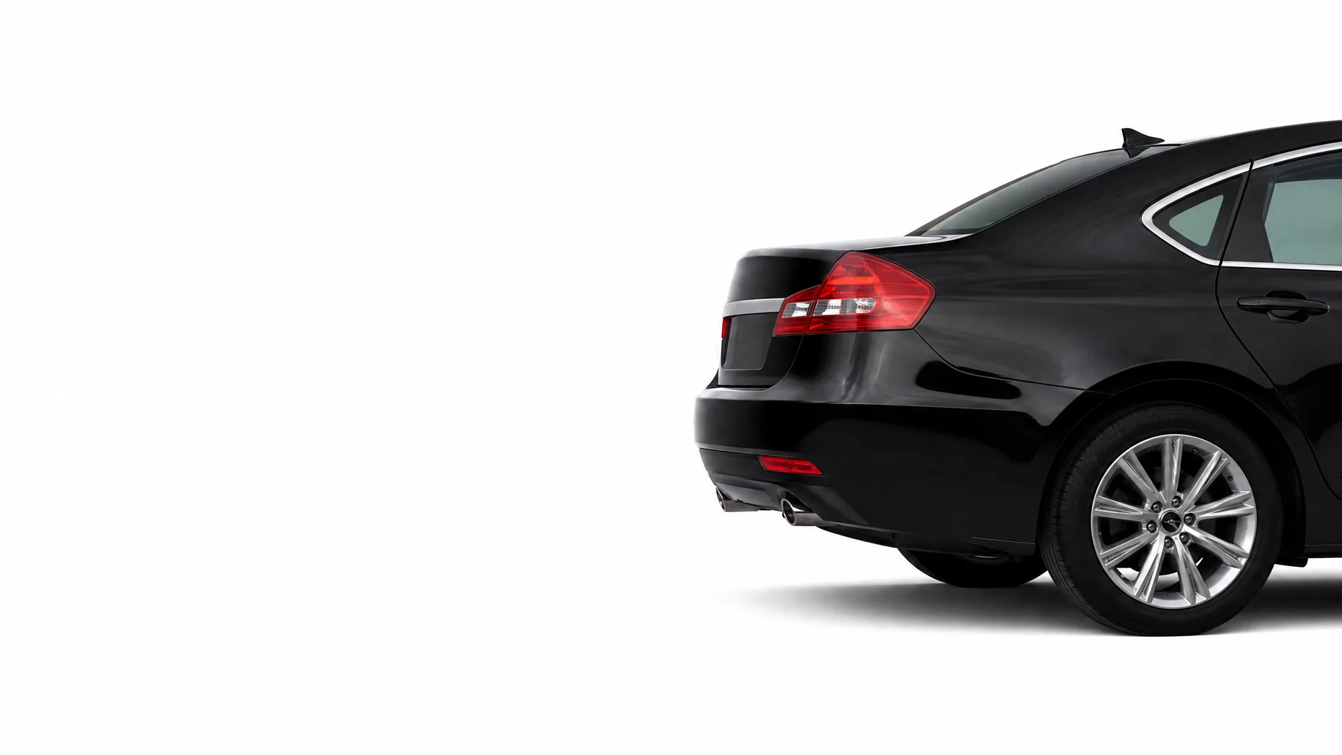 Rear three-quarter view of a black four-door sedan with alloy wheels, photographed against a plain white background.