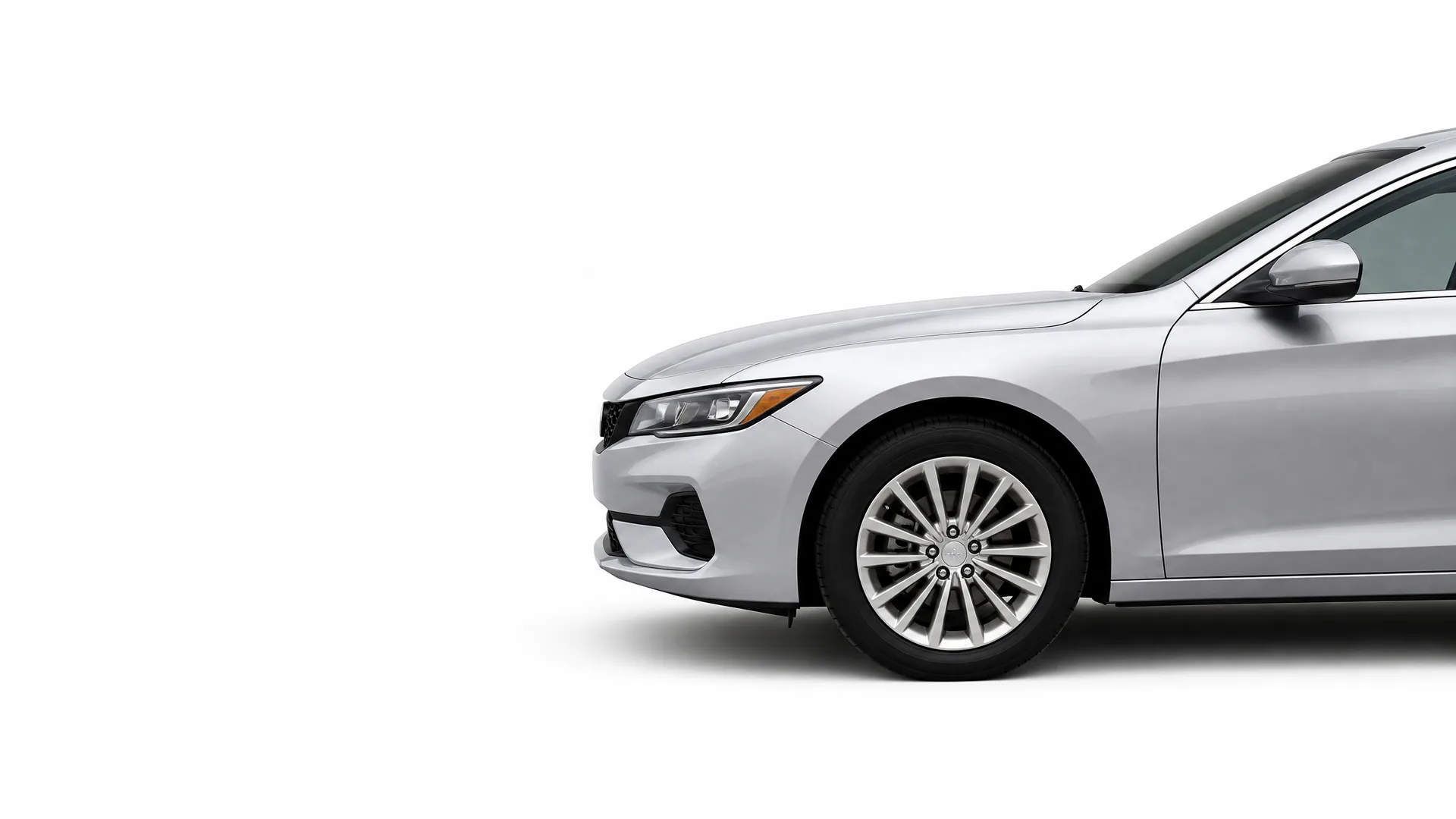 Front half of a silver four-door sedan, showing the headlight, front bumper, front wheel and side mirror, against a plain white background.