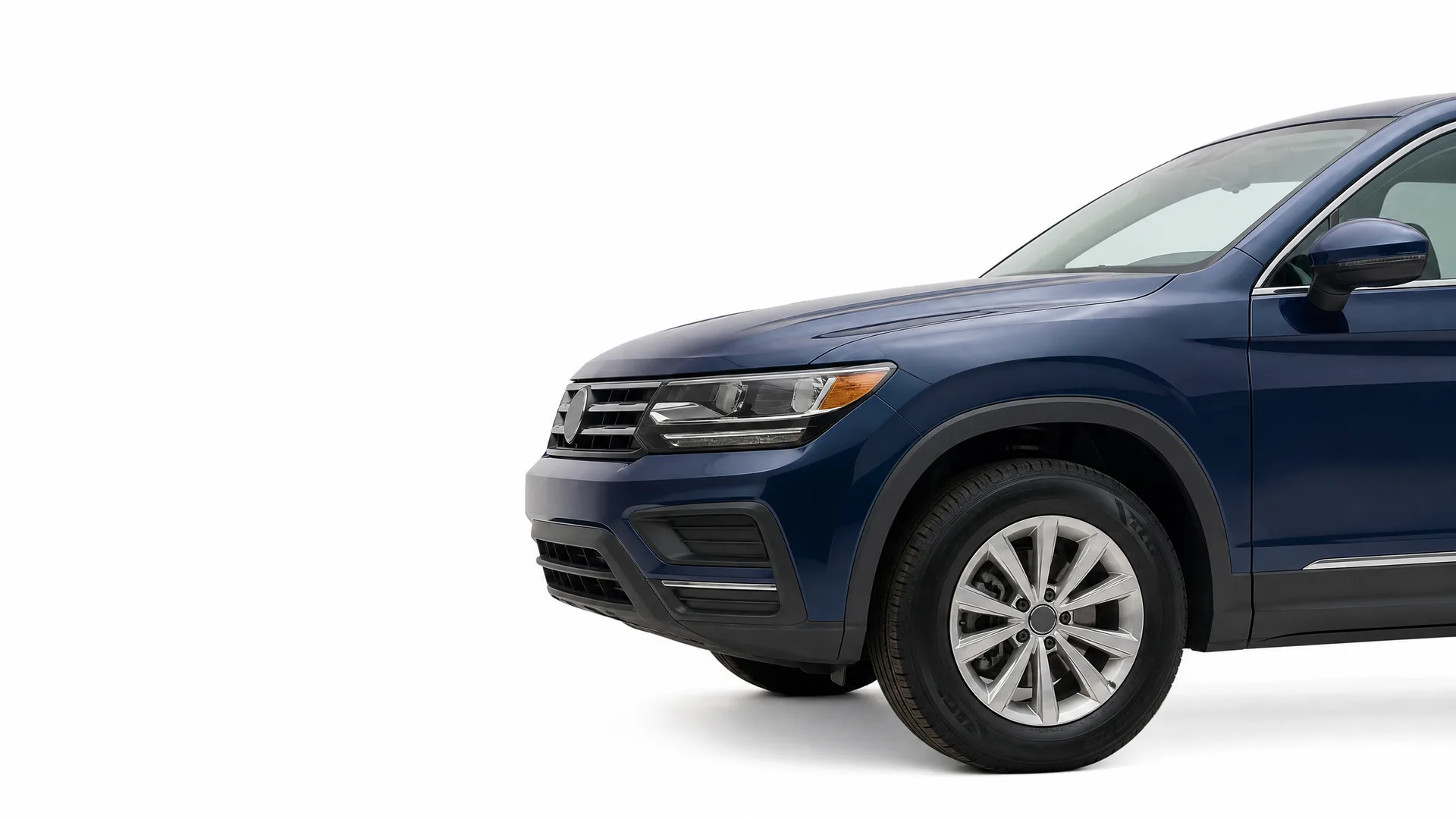 Front half of a dark blue SUV, showing the headlight, grille, front wheel and driver-side mirror, photographed against a plain white background.