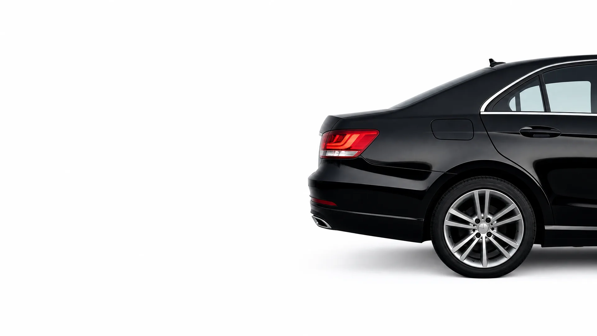 Rear three-quarter view of a black sedan's back half, showing the taillight, rear bumper, and multi-spoke alloy wheel, against a plain white background.