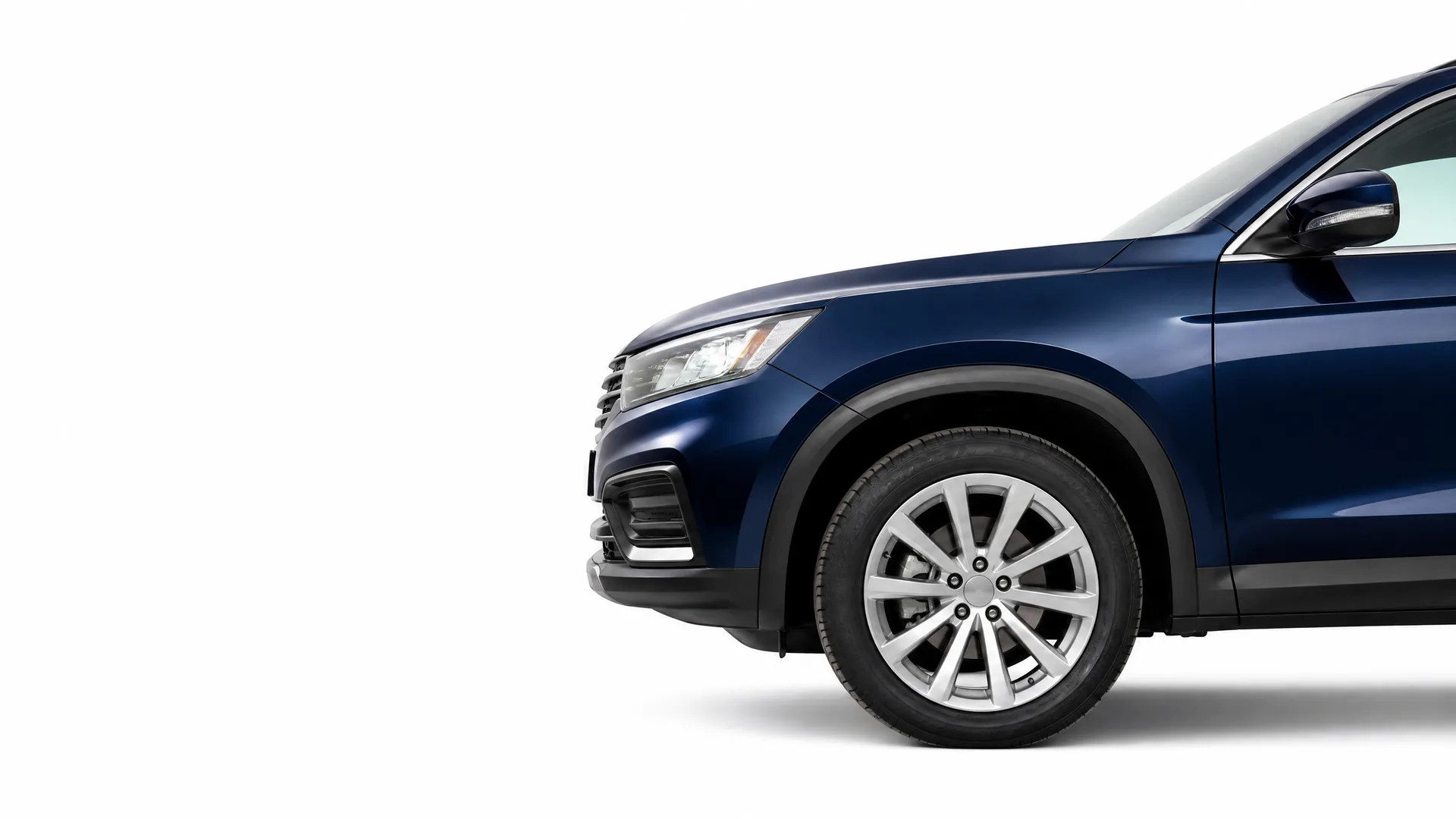 Front portion of a dark blue SUV, showing the headlight, grille, front bumper, wing mirror and front wheel with a multi-spoke alloy rim, against a plain white background.
