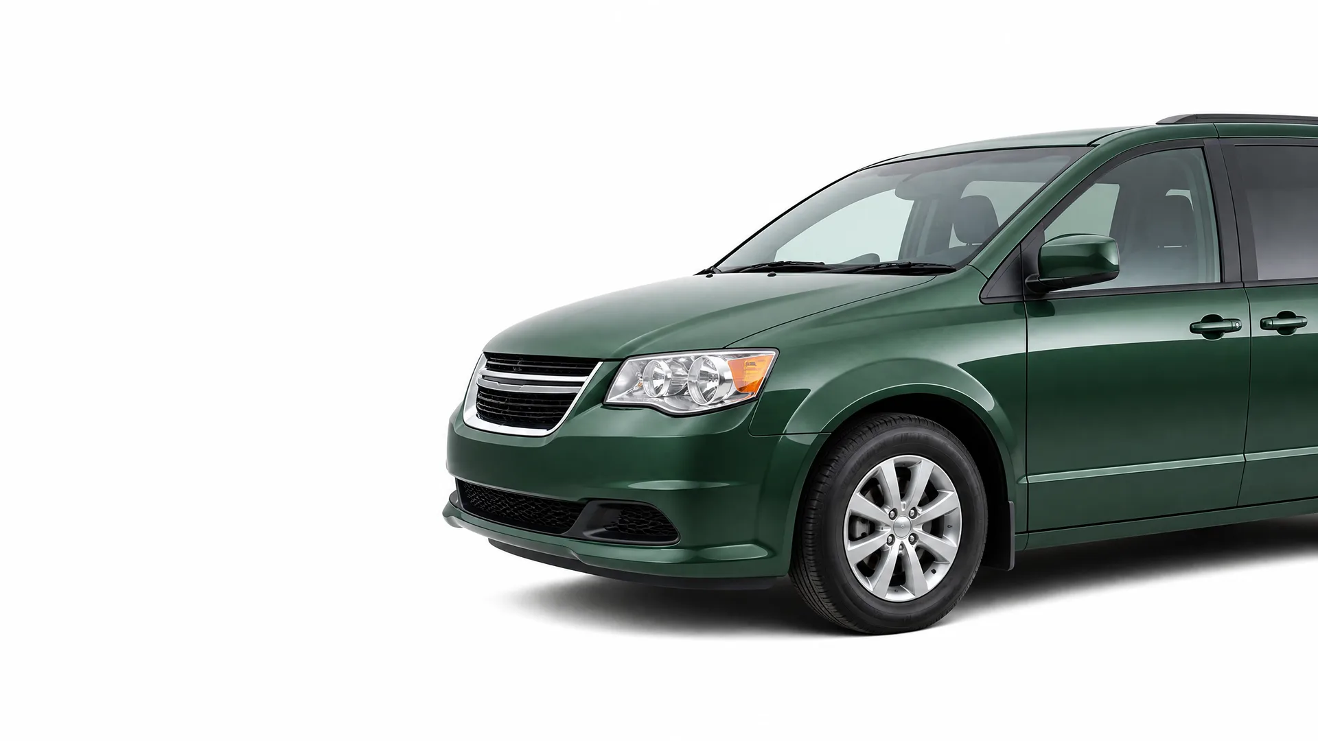 Front three-quarter view of a dark green minivan, partially cropped at the rear, against a plain white background.