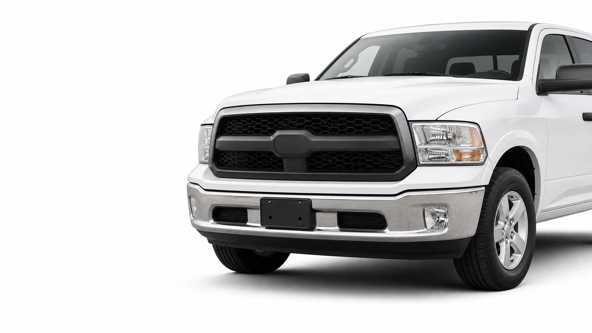 Front three-quarter view of a white crew-cab pickup truck with a black honeycomb grille, chrome bumper and blank license plate holder, photographed against a plain white background.