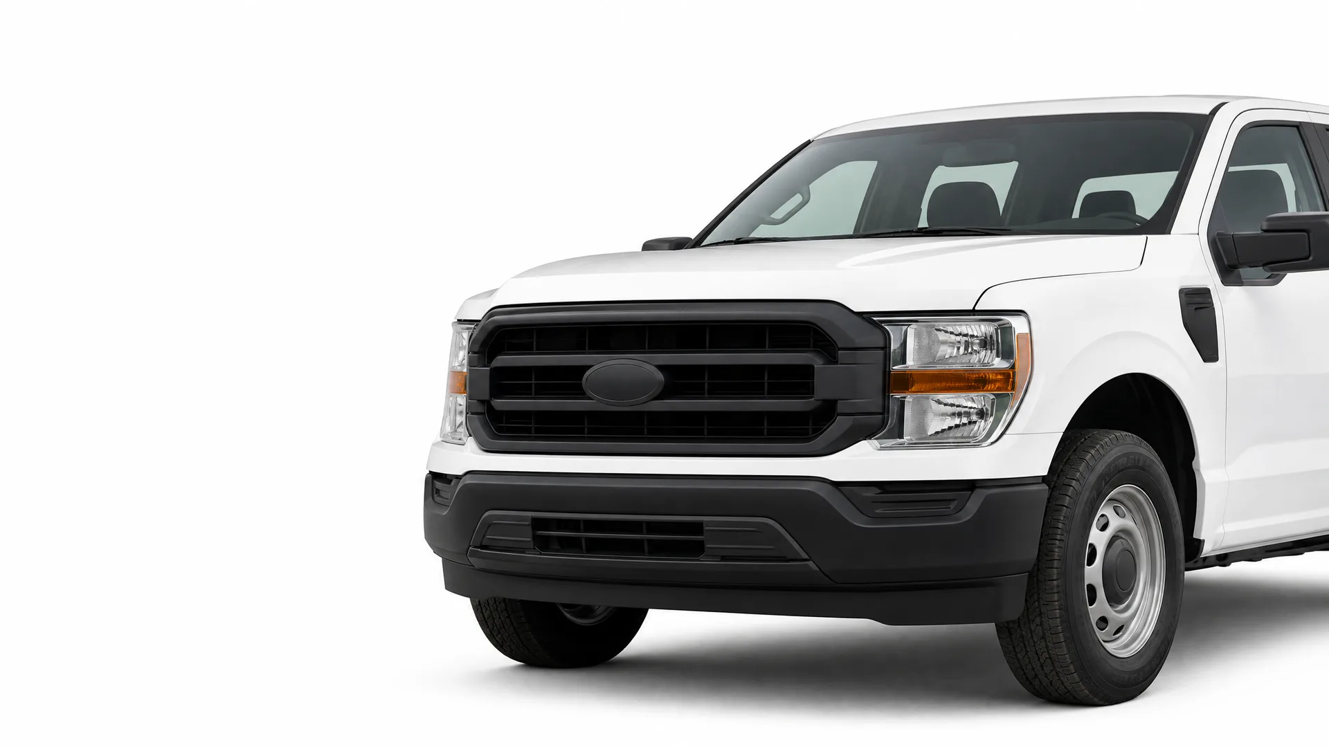 Front three-quarter view of the front half of a white pickup truck with a black grille, steel wheels, and an oval badge on the grille, against a plain white background.