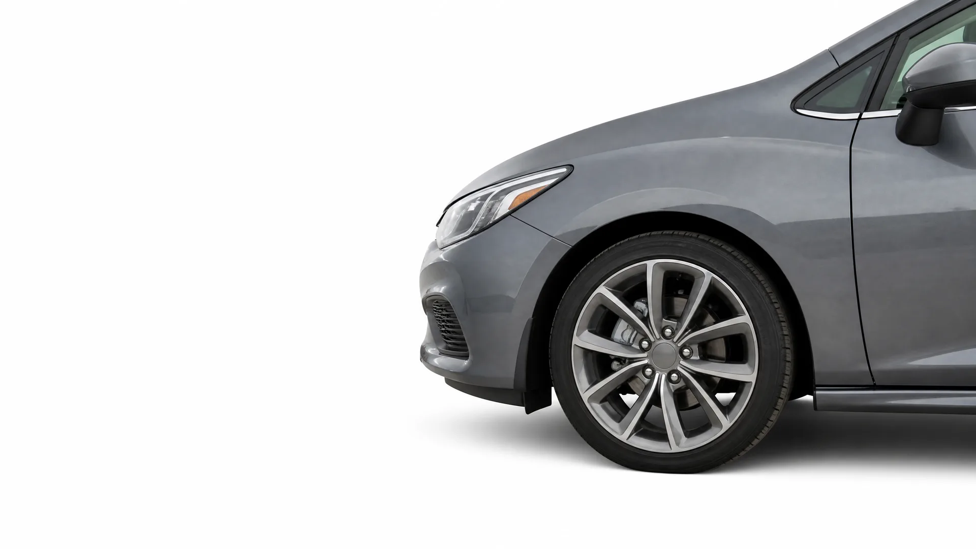 Partial view of the front left side of a gray sedan, showing the headlight, front bumper, and alloy wheel, against a plain white background.