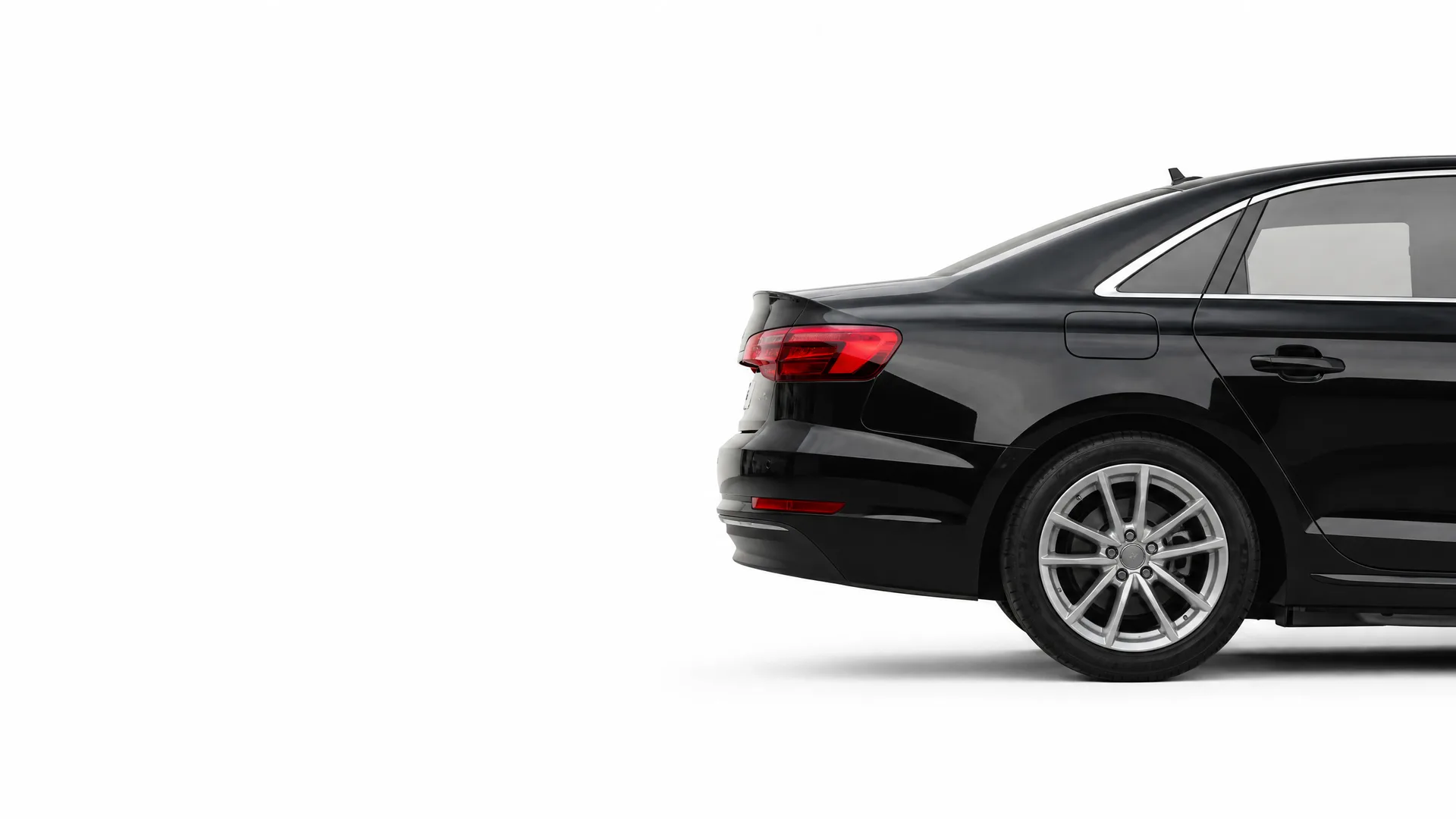 Rear three-quarter view of a black four-door sedan with alloy wheels, shown against a plain white background with a soft shadow beneath it.