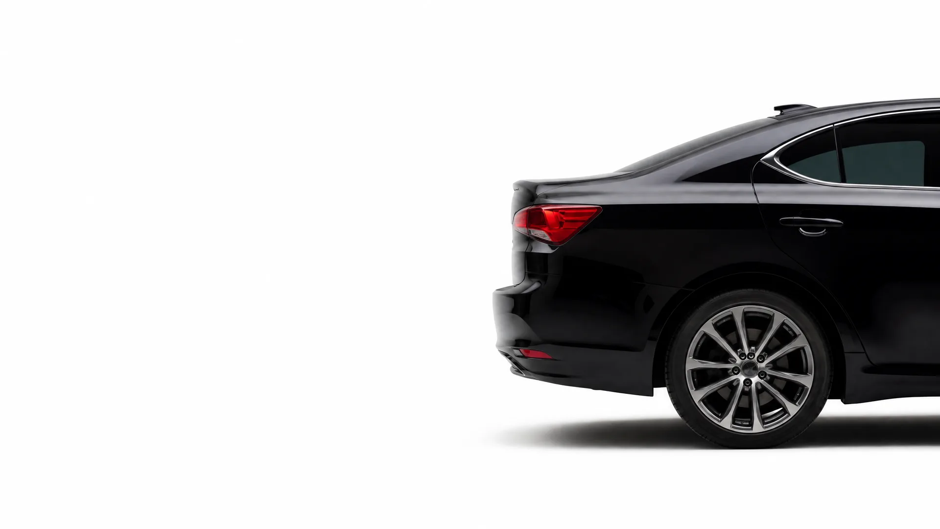 Rear half of a black sedan with a red taillight and multi-spoke alloy wheel, shown against a plain white background.