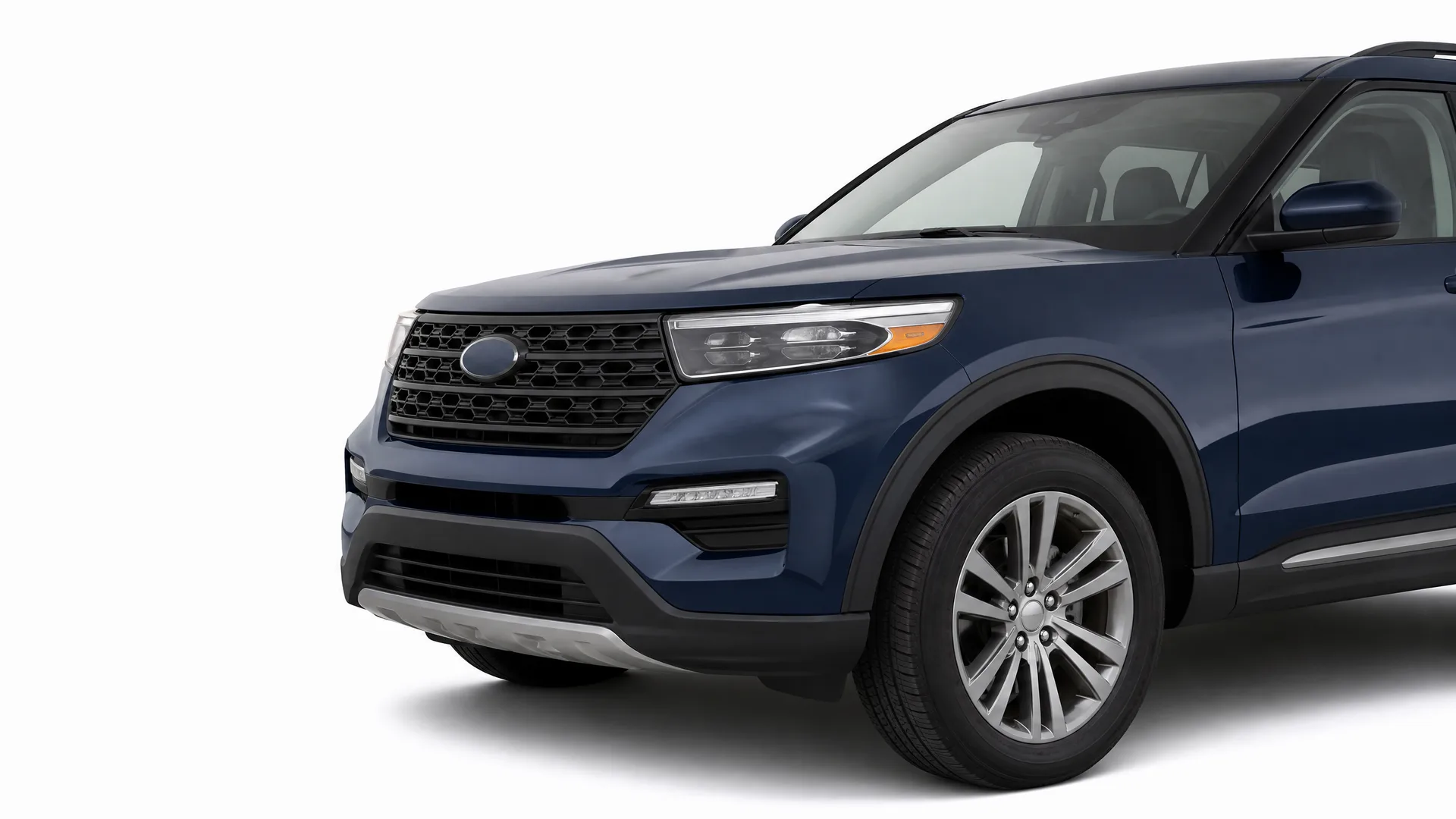 Front three-quarter view of a dark blue SUV with alloy wheels and a black mesh grille, photographed against a plain white background.