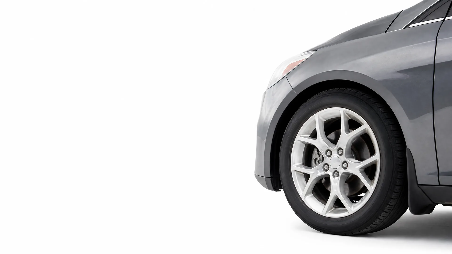Front portion of a dark gray car, showing the front wheel with a multi-spoke alloy wheel, fender and lower door, against a plain white background.