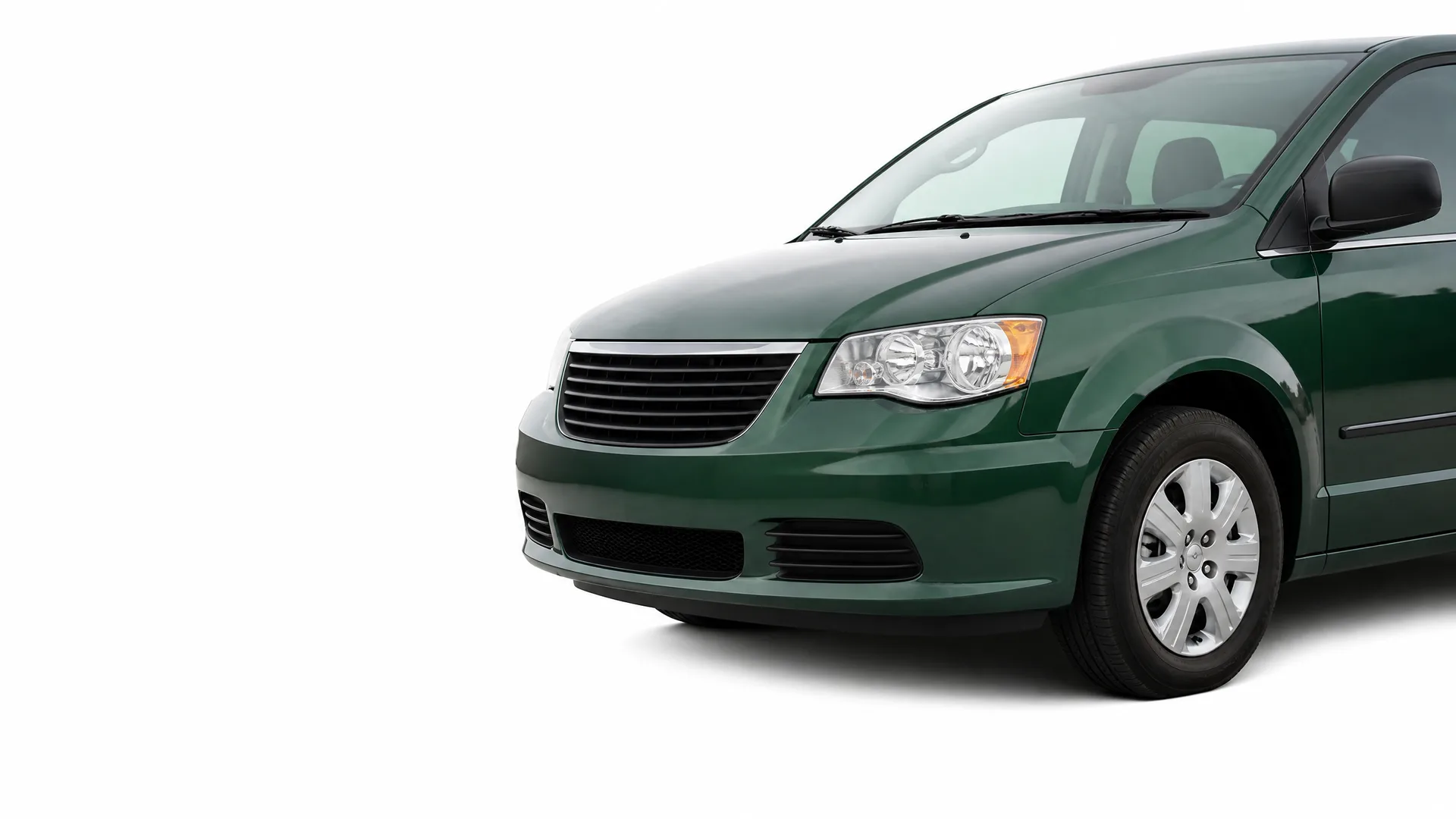 Front three-quarter view of a dark green minivan against a plain white background, showing the hood, grille, headlight, front wheel and driver-side mirror.