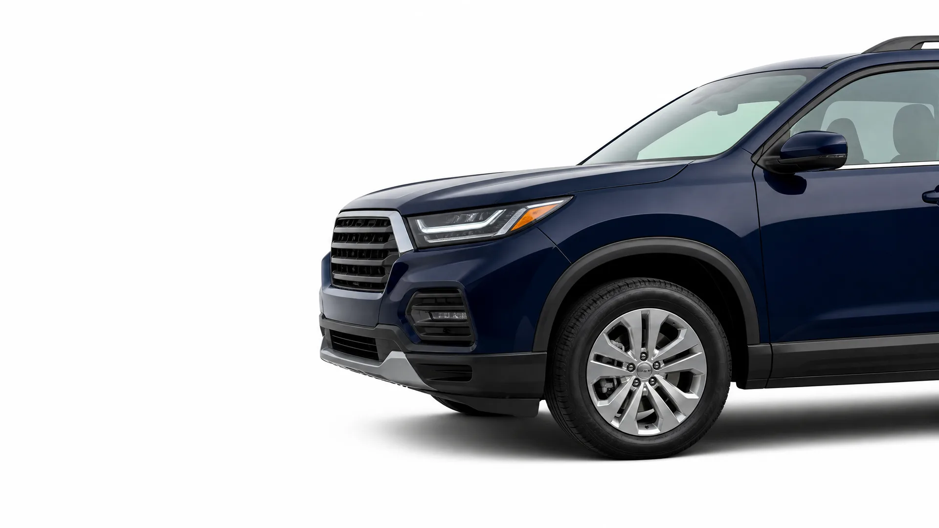 Front three-quarter partial view of a dark blue SUV against a plain white background, showing the grille, headlight, front wheel and driver-side doors.