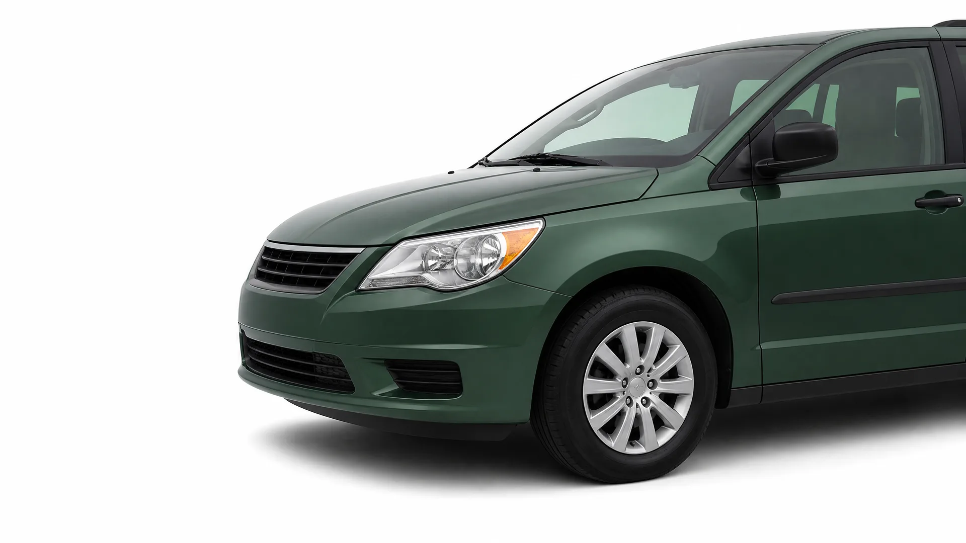 Front three-quarter view of the front half of a dark green minivan on a plain white background.