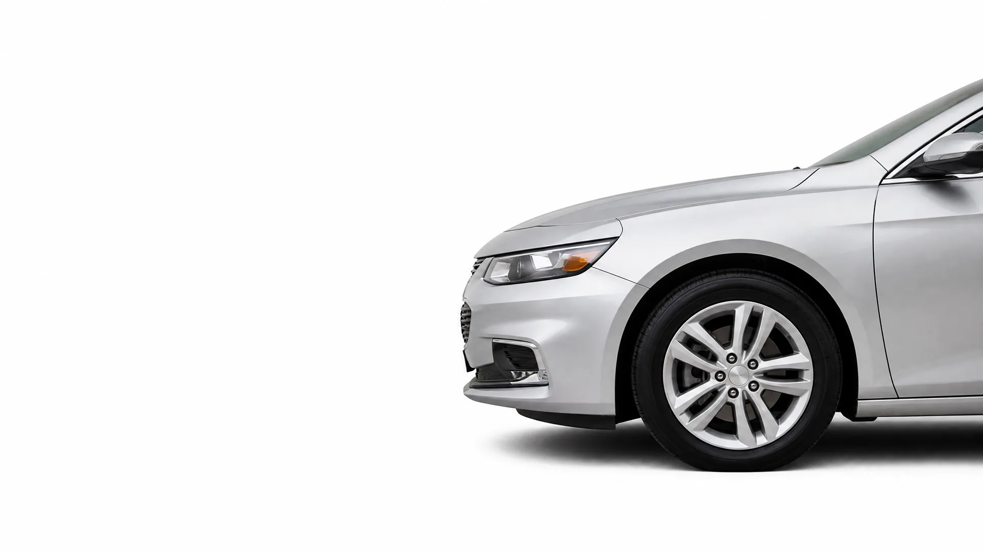 Front portion of a silver sedan, showing the headlight, front bumper, hood and front wheel, photographed against a plain white background.