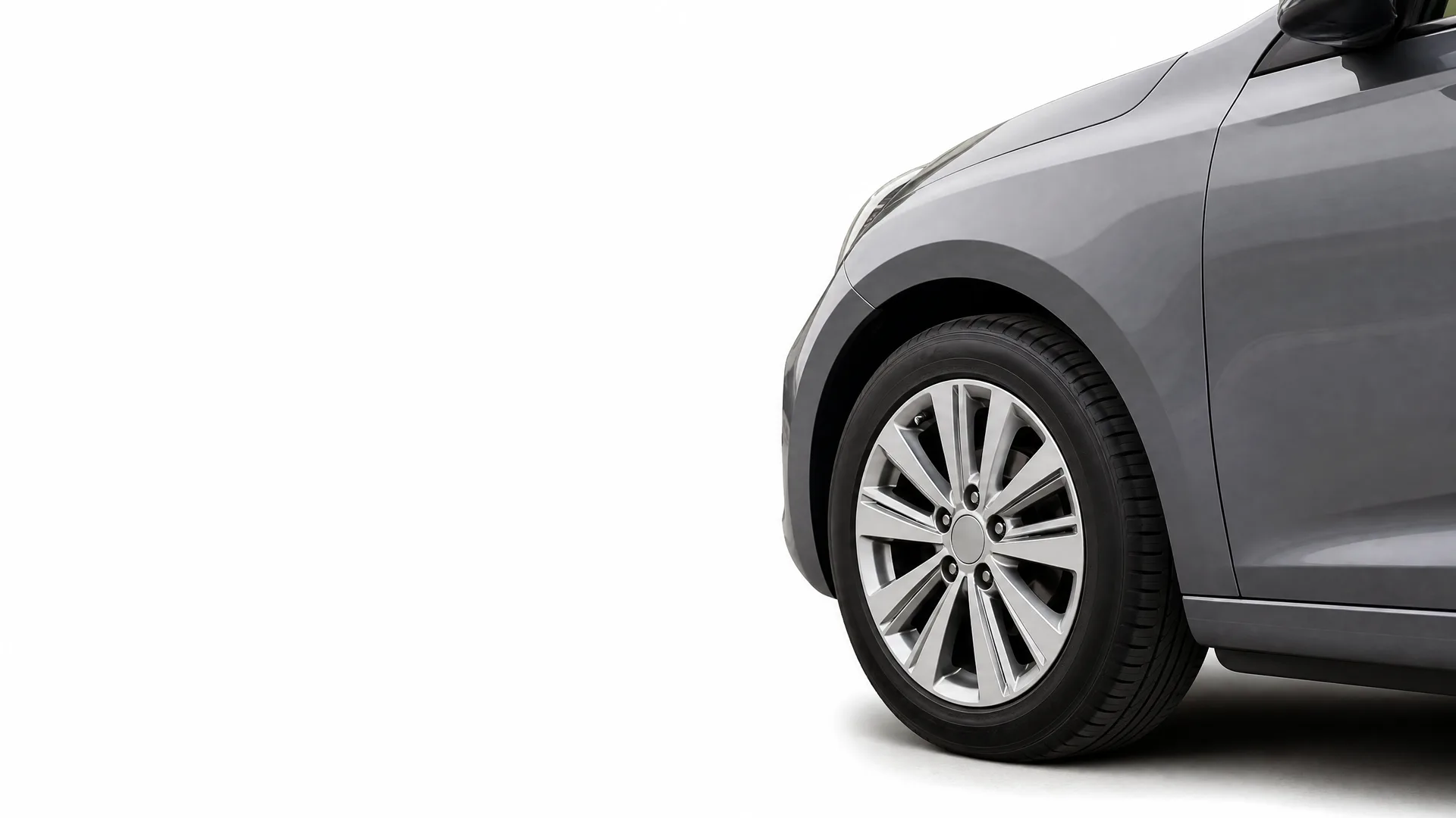 Front section of a gray car, showing the front wheel with a multi-spoke alloy wheel, fender and part of the door, isolated on a white background.