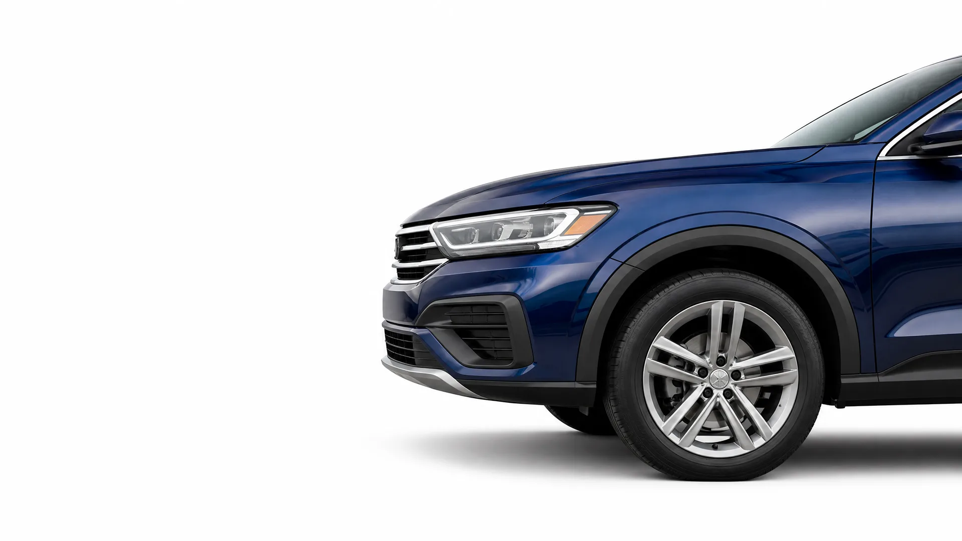 Front portion of a dark blue SUV, showing the headlight, grille, bumper and front wheel, photographed against a plain white background with a soft shadow.