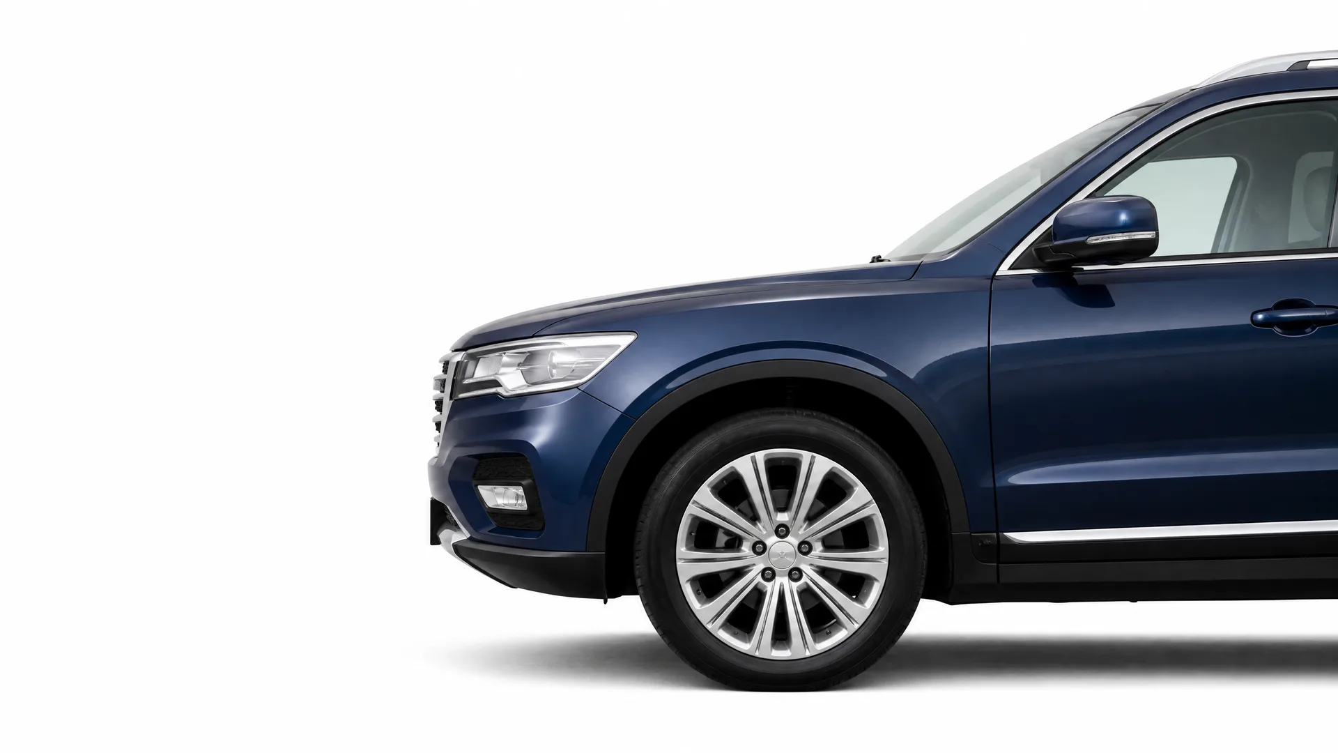 Partial side view of the front half of a dark blue SUV, showing the headlight, front wheel with multi-spoke alloy rim, side mirror and front door, against a plain white background.