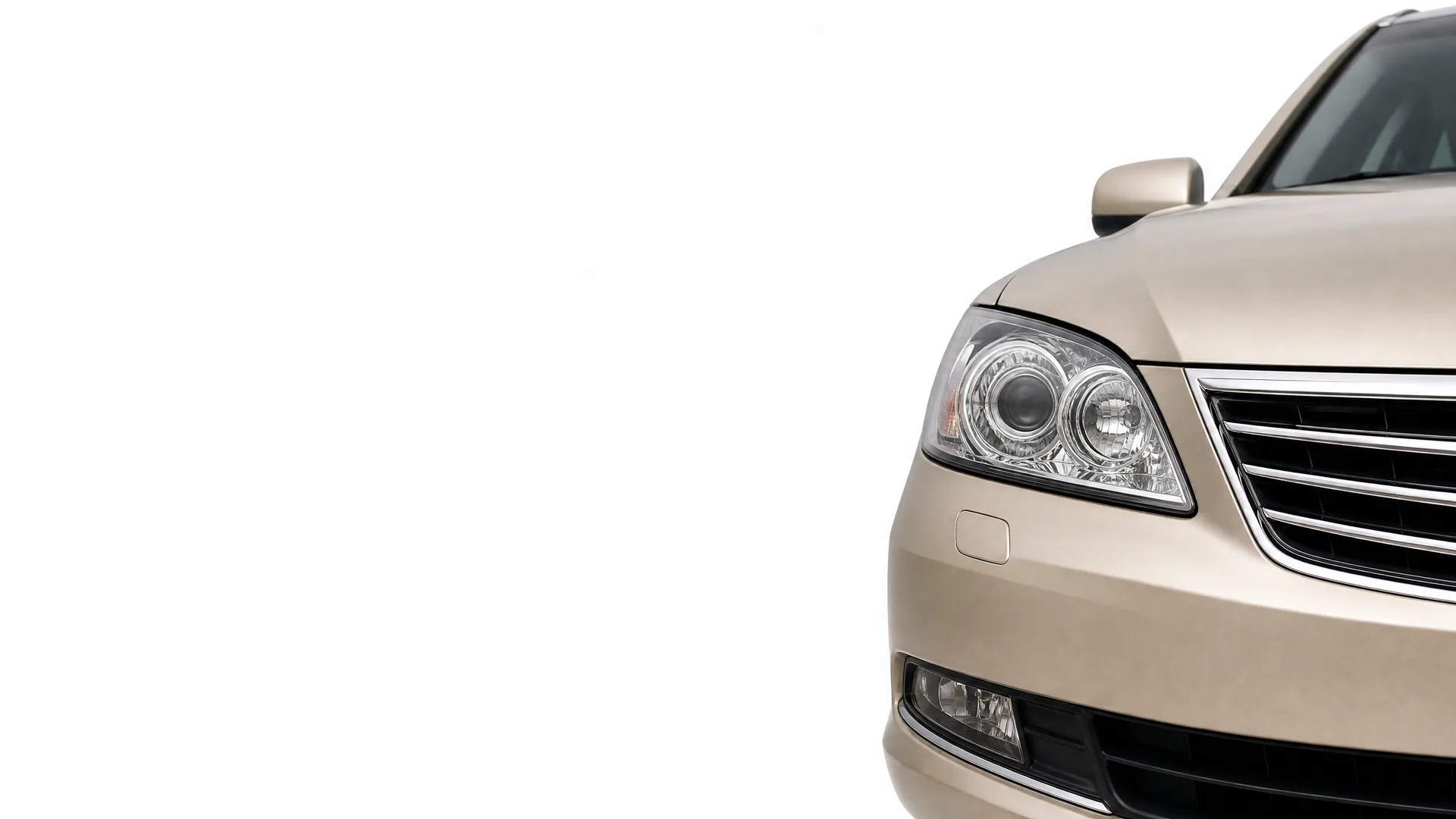 Front right portion of a beige sedan, showing the headlight, grille, bumper and side mirror, against a white background.