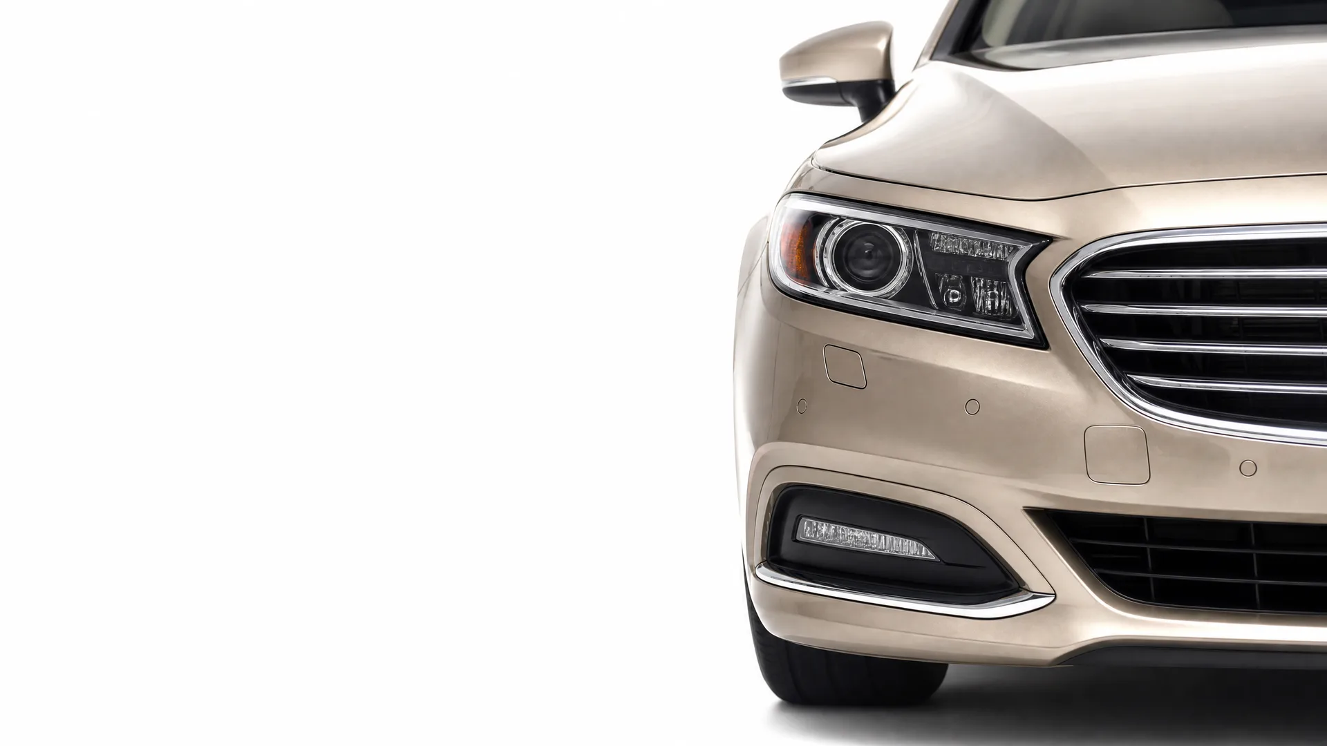 Front right portion of a champagne-colored sedan, showing headlight, grille, bumper and fog lamp, against a plain white background.