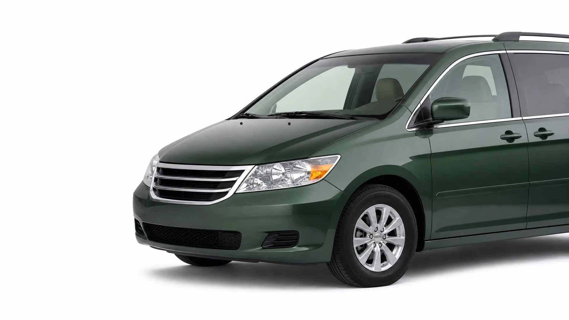 Dark green minivan shown from a front three-quarter angle against a plain white background, with the rear of the vehicle cropped off.
