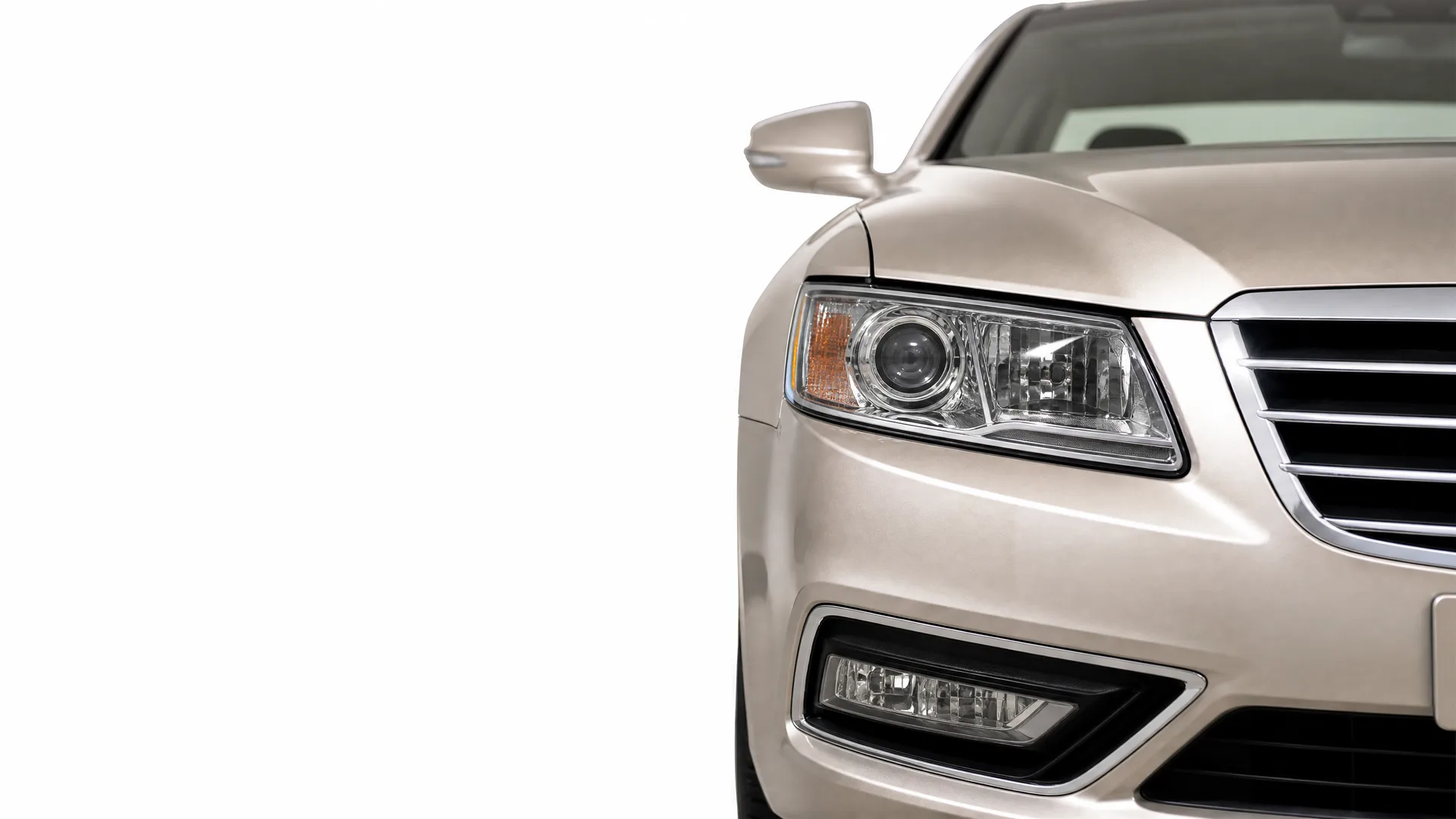 Front right portion of a beige sedan, showing the headlight, grille, fog lamp and side mirror, isolated on a white background.