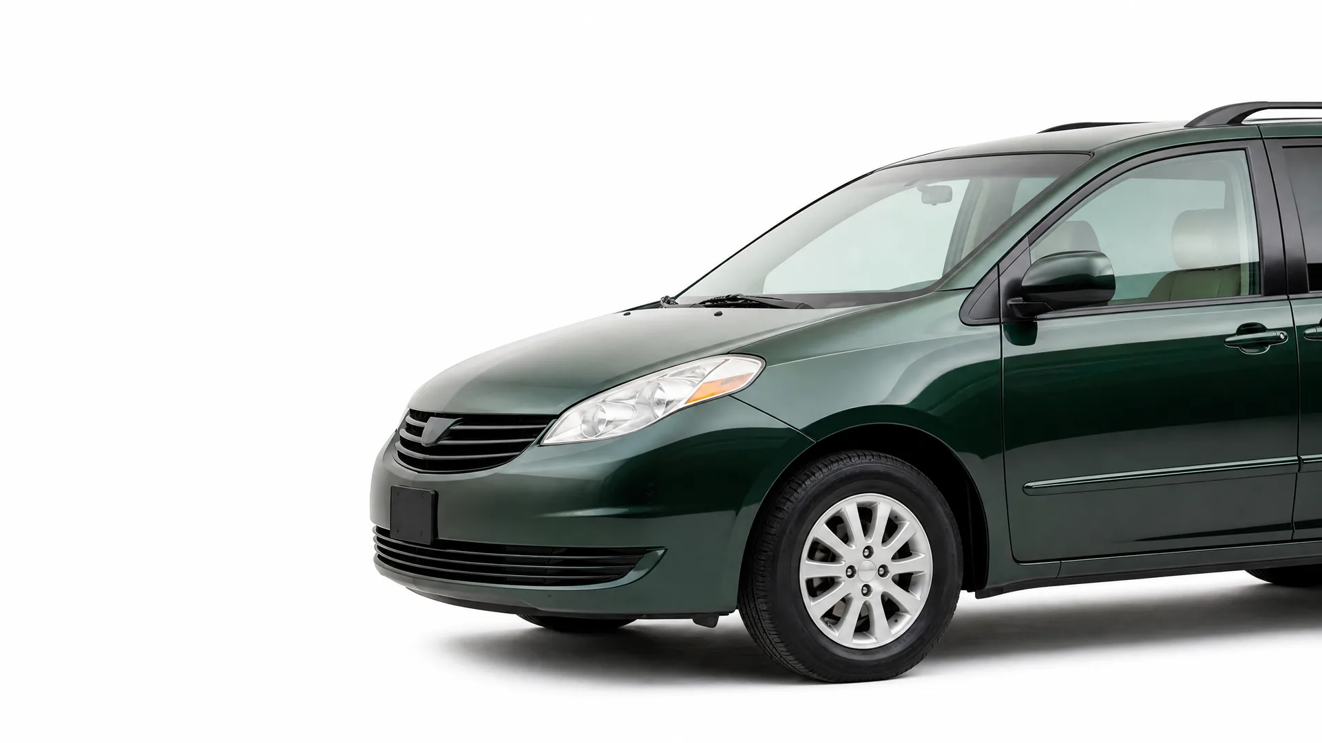 Front three-quarter view of a dark green minivan with alloy wheels and roof rails, photographed against a plain white background.