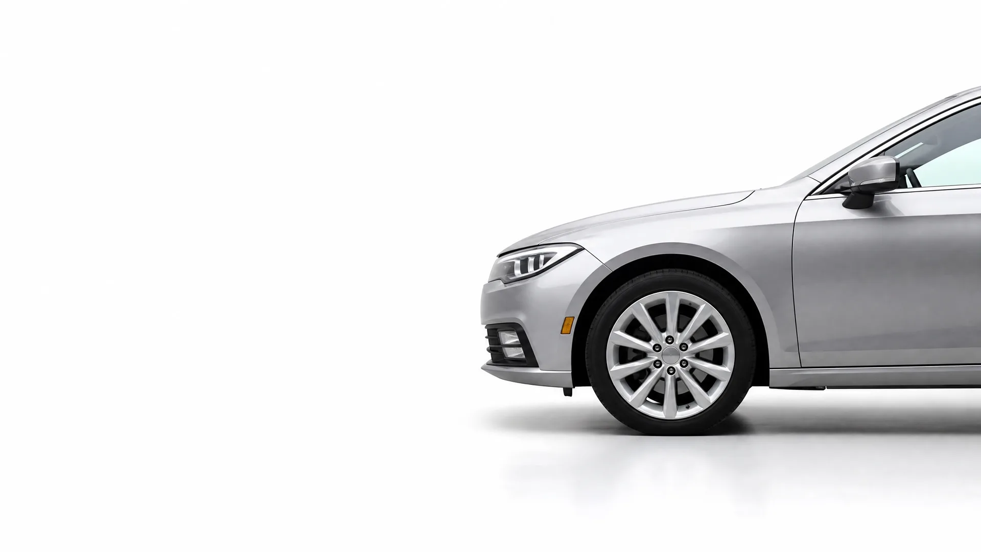Front half of a silver sedan, shown in profile with its front wheel and headlight, against a plain white background.