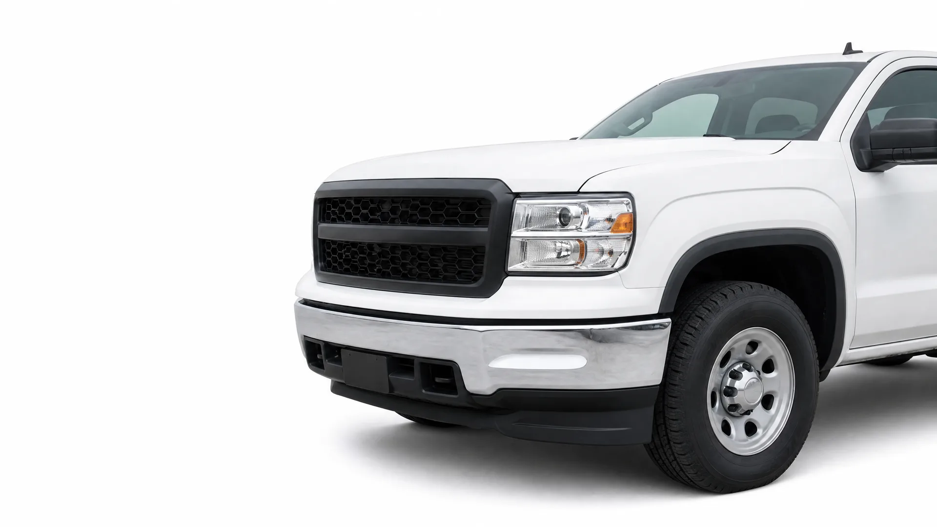 Front three-quarter view of the left side of a white pickup truck with a black grille and chrome bumper, isolated on a white background.