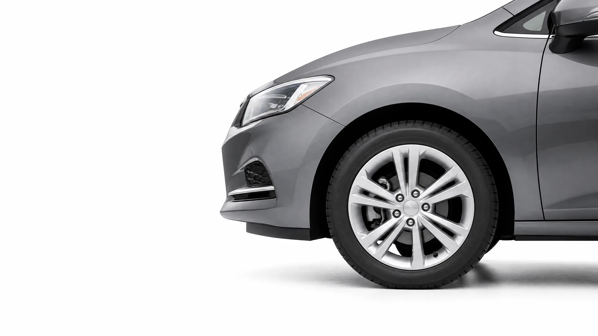 Front half of a gray sedan, showing the headlight, front bumper, and alloy front wheel, against a plain white background.