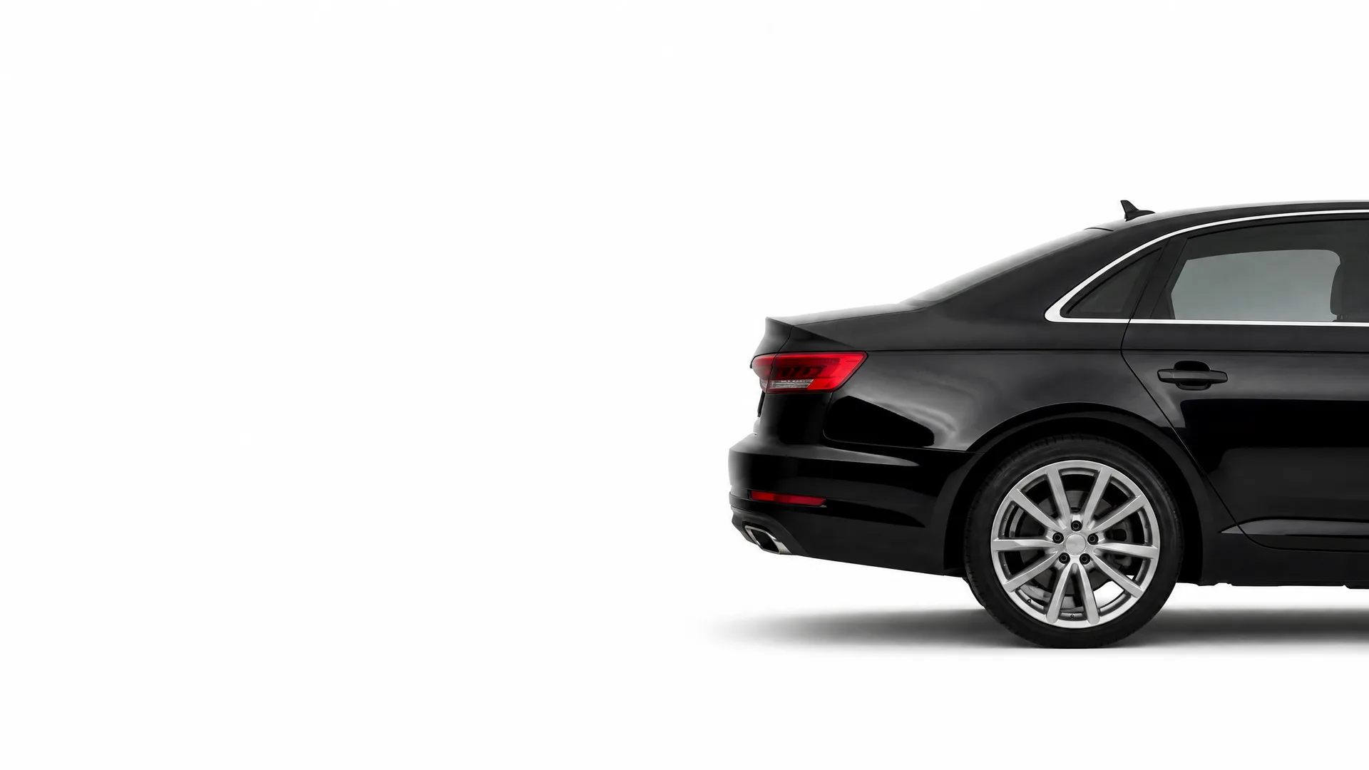 Rear three-quarter view of a black sedan partially cropped at the right edge of a plain white background.