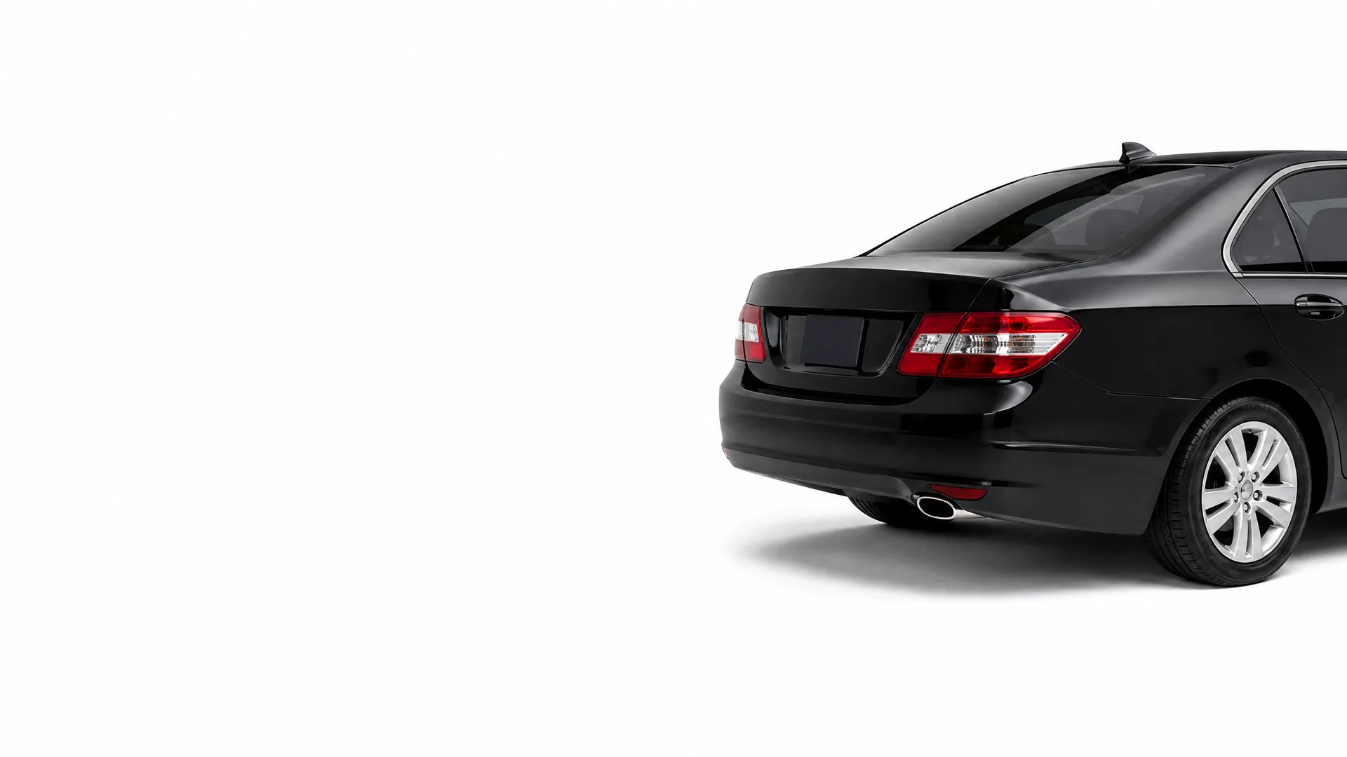 Rear three-quarter view of a black four-door sedan on a plain white background with a soft shadow beneath it.