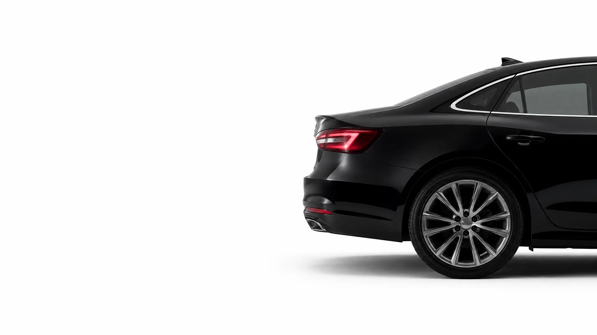 Rear three-quarter view of a black sedan's back end, taillight and multi-spoke alloy wheel against a plain white background.