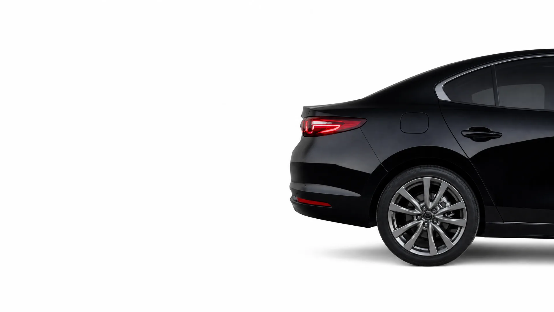 Rear three-quarter view of a black four-door sedan with alloy wheels, cropped at the front, against a plain white background.