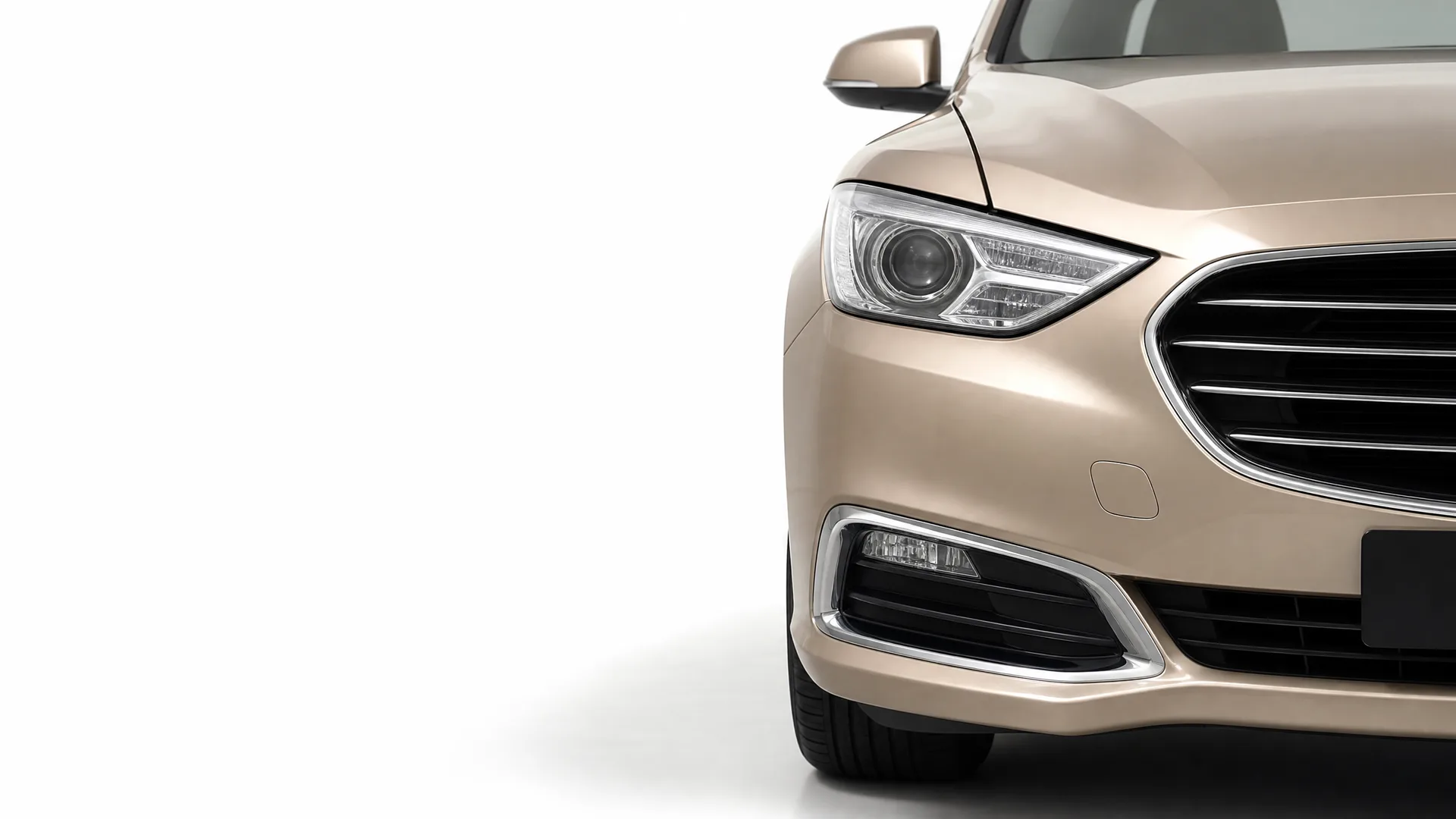 Front right section of a beige sedan, showing headlight, grille, fog light and wheel, against a plain white background.