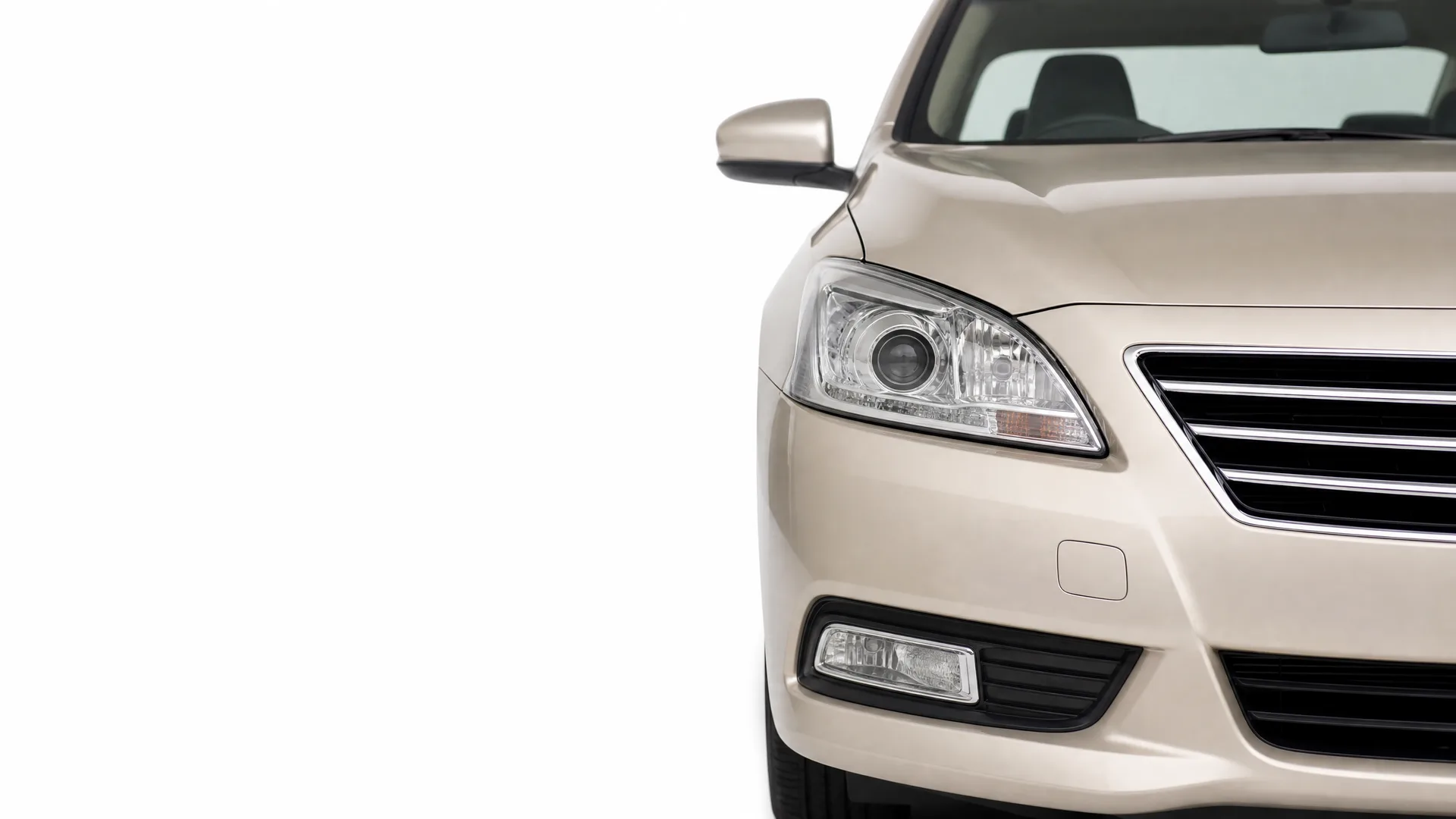 Front left portion of a beige sedan, showing the headlight, grille, fog light, side mirror and windshield, against a plain white background.