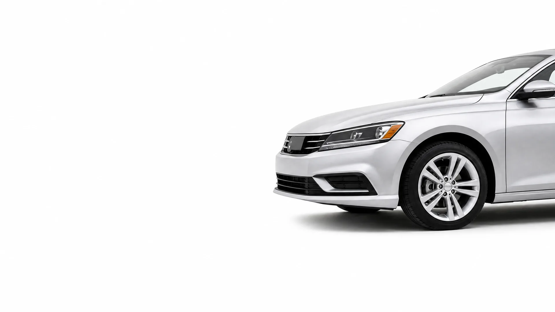 Front portion of a silver four-door sedan, showing the headlight, grille, front bumper and front wheel, against a plain white background.