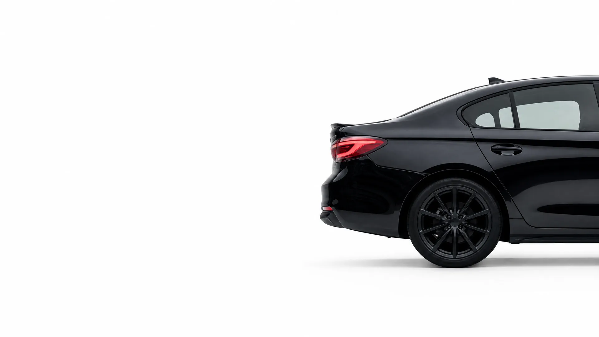 Rear half of a black four-door sedan with dark alloy wheels and tinted windows, shown in profile against a plain white background.