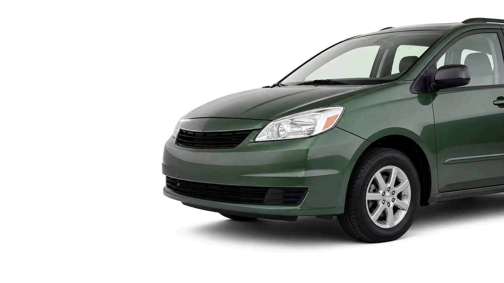 Front three-quarter view of a dark green minivan, partially cropped at the rear, photographed against a plain white background with a soft shadow beneath.