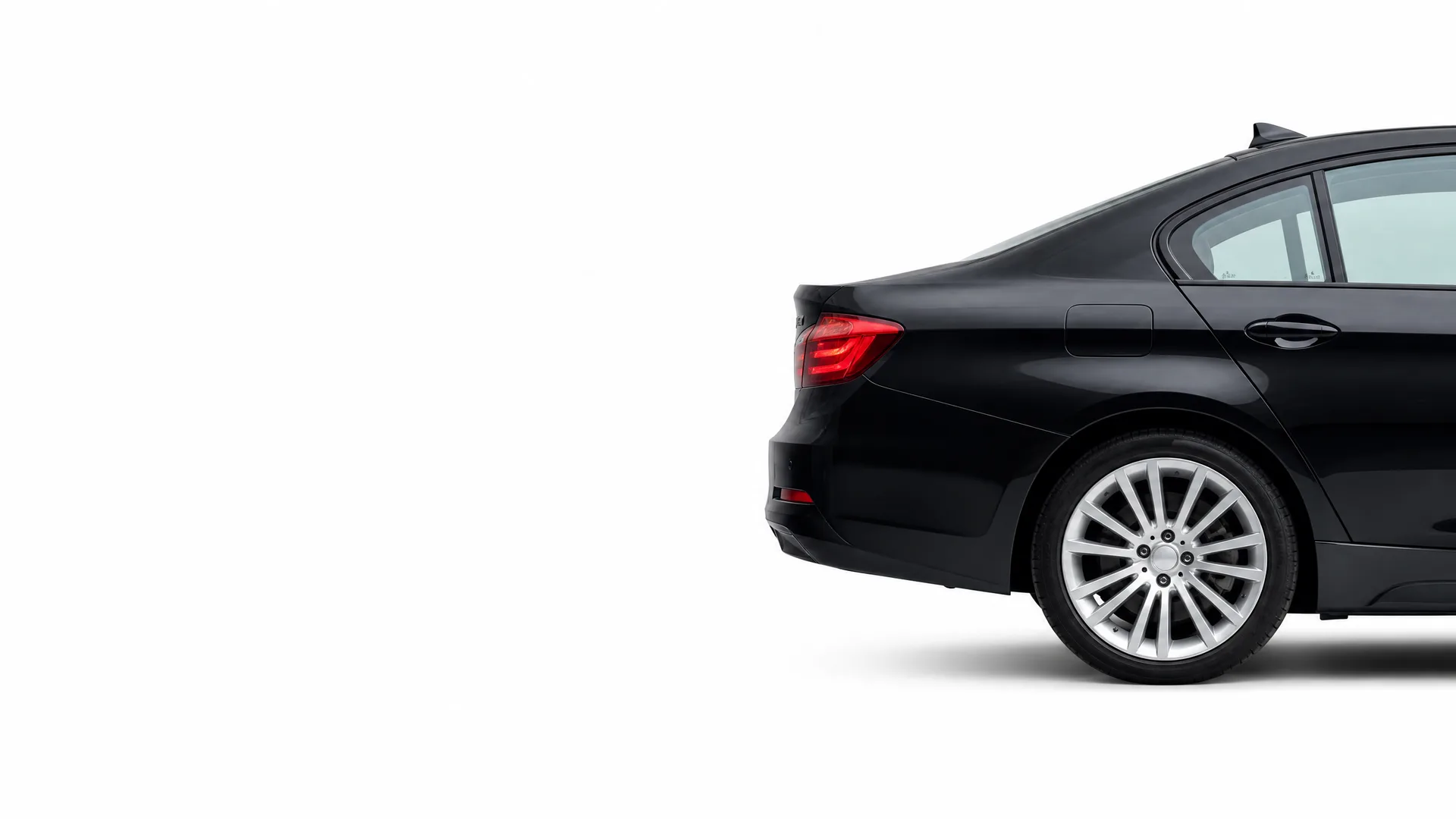 Rear three-quarter view of a black four-door sedan with multi-spoke alloy wheels, shown against a plain white background.