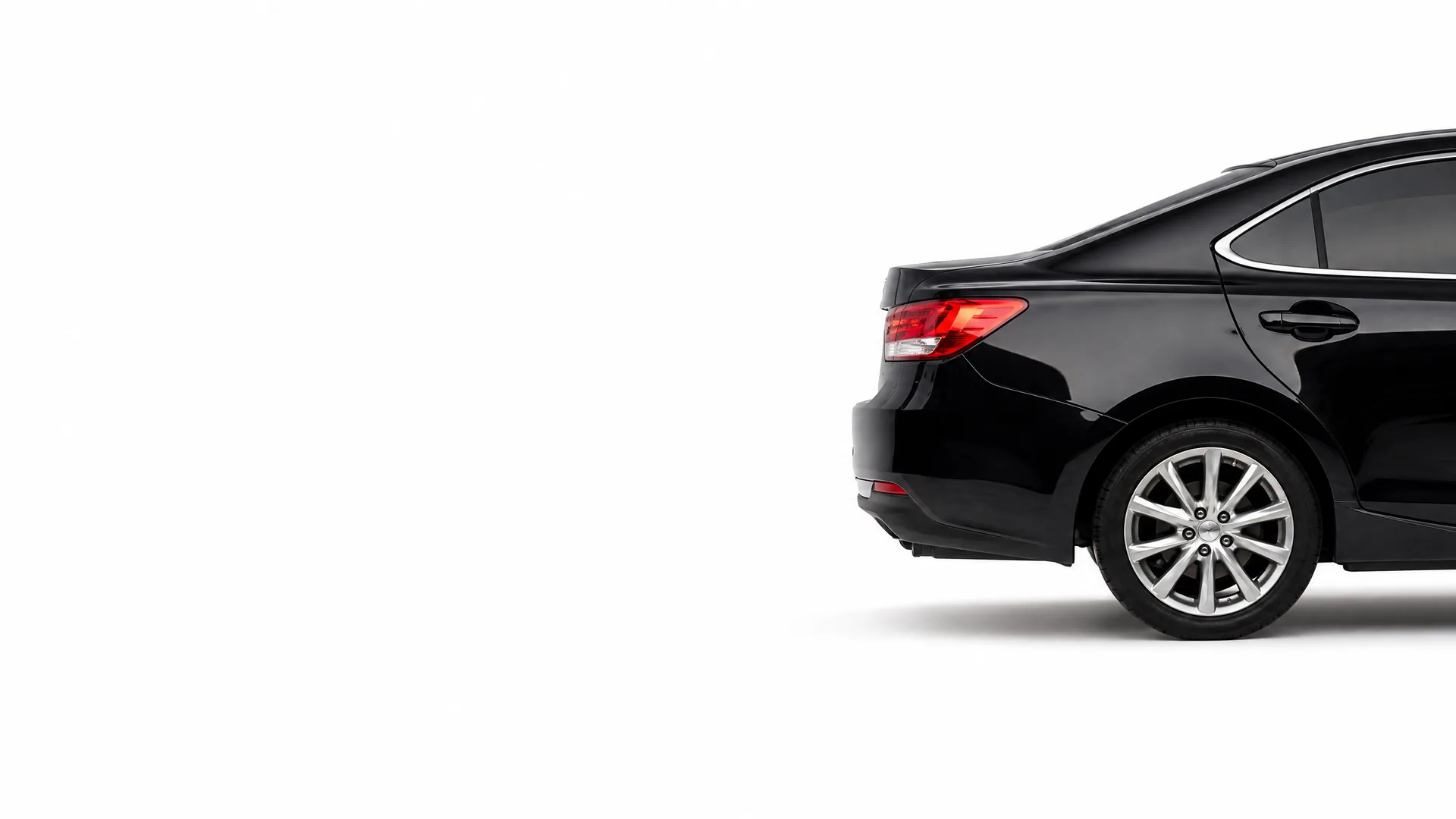 Rear half of a black sedan, showing the taillight, rear wheel with multi-spoke alloy rim, and rear door, against a plain white background.